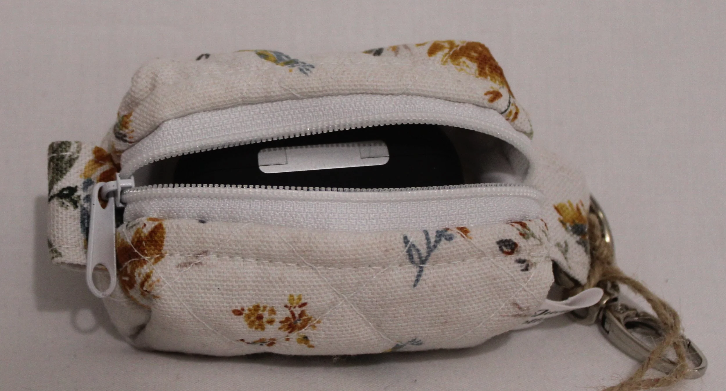 Top open view of the Dandelion Blue Bag Charm featuring assorted dandelions on an off white background and shown with a set of Airpod Pro earbuds inserted for size reference.
