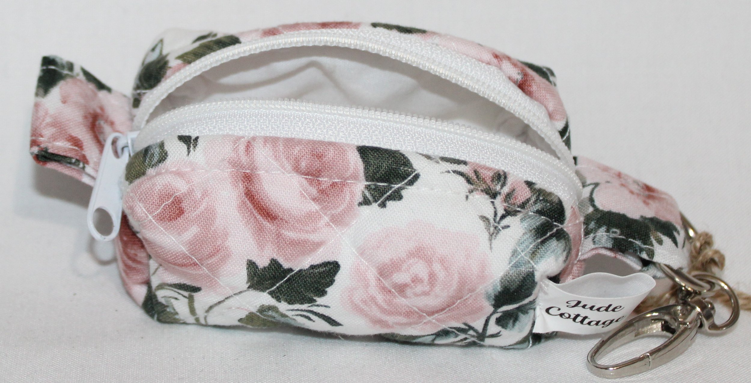 Open top view of the Rose Garden Bag Charm featuring white fabric with pink rose print showing white zip closure and lining.