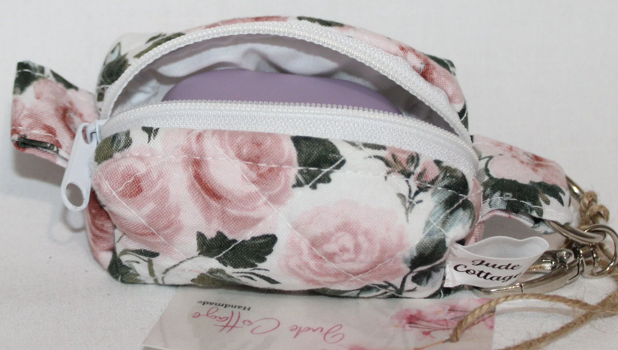 Open top view of the Rose Garden Bag Charm featuring white fabric with pink rose print shown with a J Lab earbud case inserted for size reference.