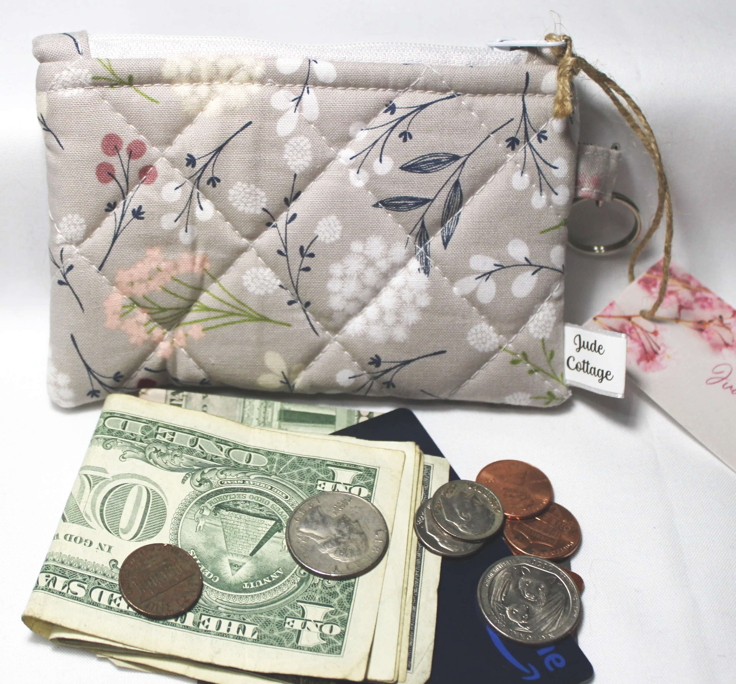 Front view of Dandelion Field quilted keychain wallet with floral pattern, with cash, coins and cards pictured to show use.