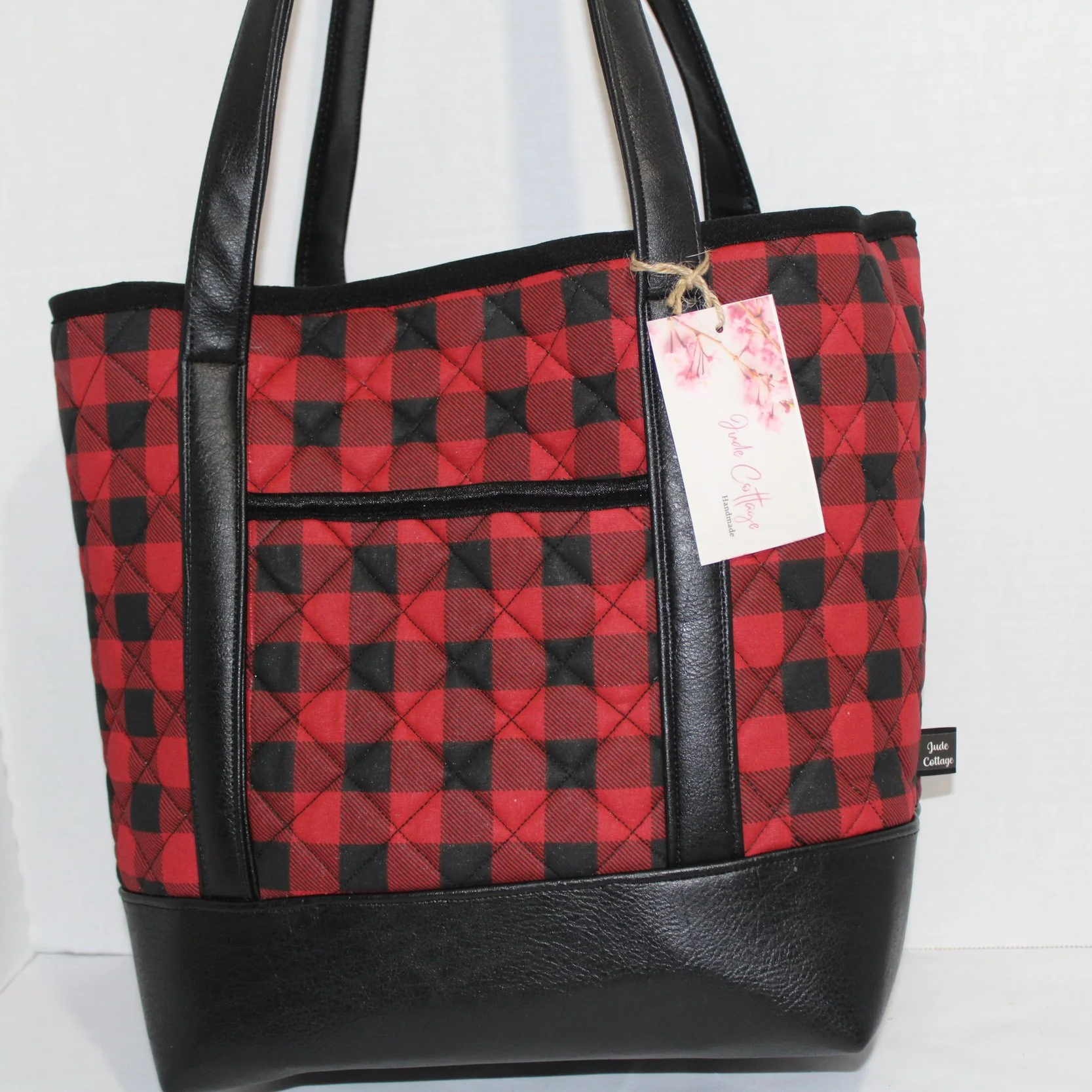 Front view of the Buffalo Red quilted tote bag featuring black faux leather combined with red and black buffalo print fabric, showing the front slip pocket.