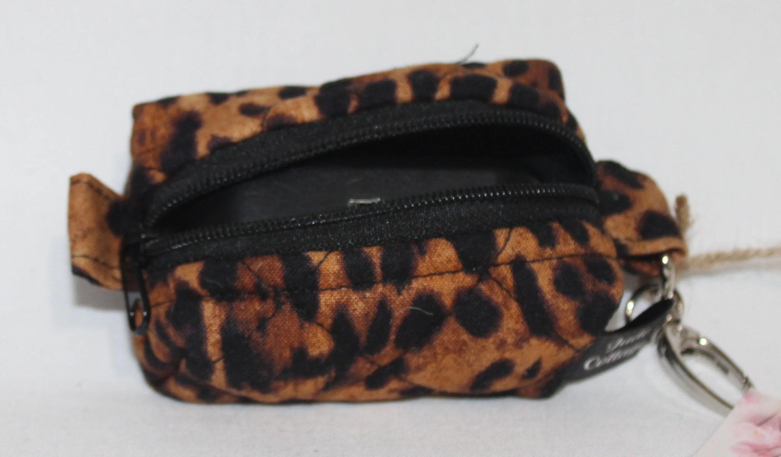 Top open view of the Lyra Bag Charm featuring a leopard print fabric and shown with a J Lab earbud case inserted for sizing reference.