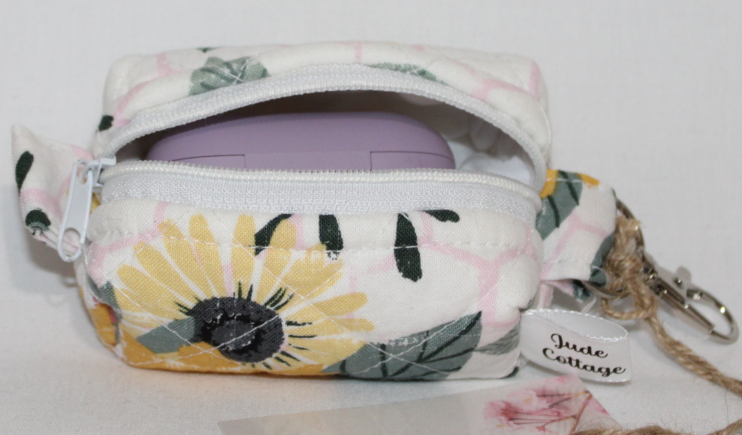 Open top view of the Honeycomb Sunflower Bag Charm featuring a white fabric with pink honeycombs and yellow sunflower print, shown with a J Lab earbud case inserted for sizing reference.