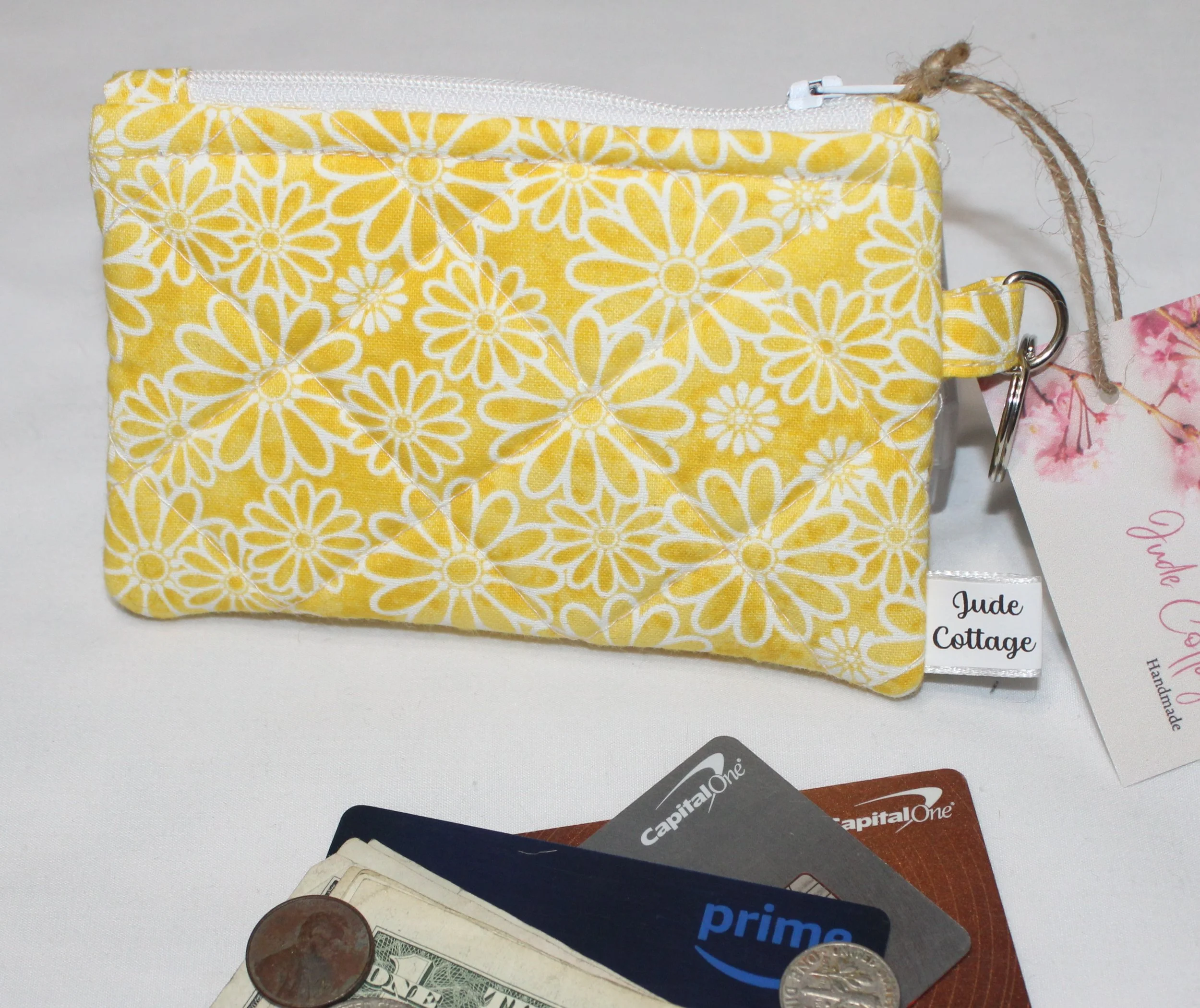Quilted keychain wallet with golden daisy pattern, zipper closure, and metal key ring.
