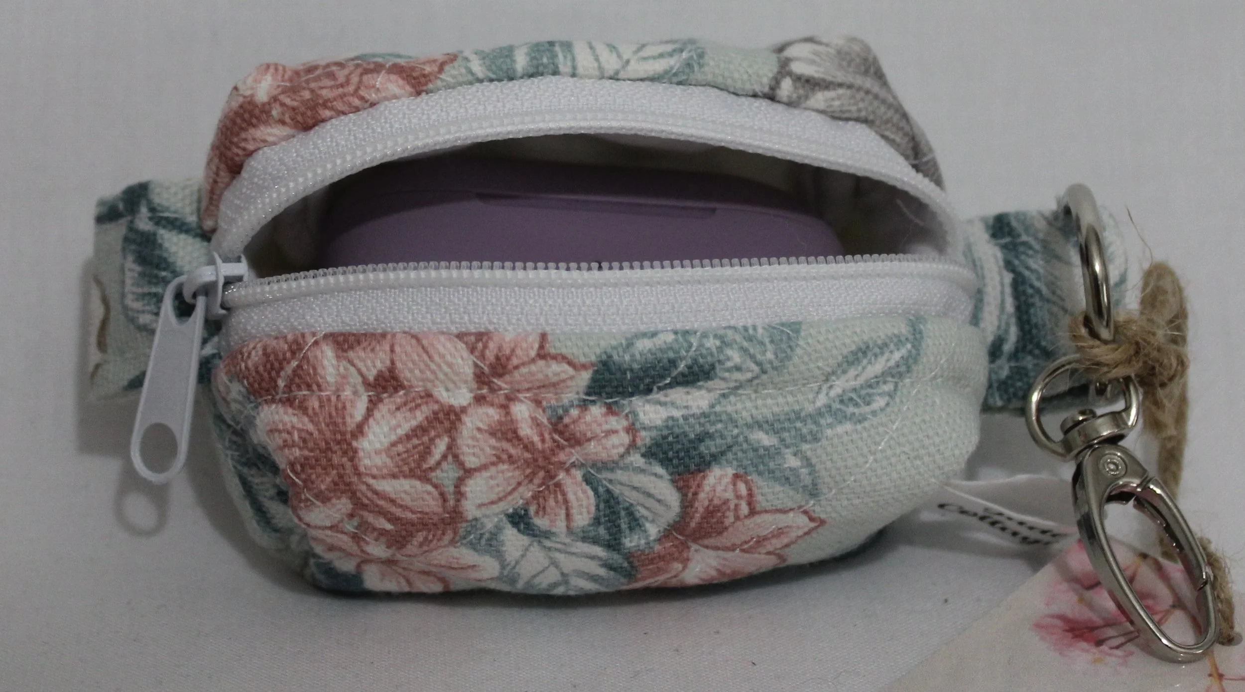 Open top view of the Joelle Bag Charm showing zip enclosure and a J Lab earbud case inserted to size reference.