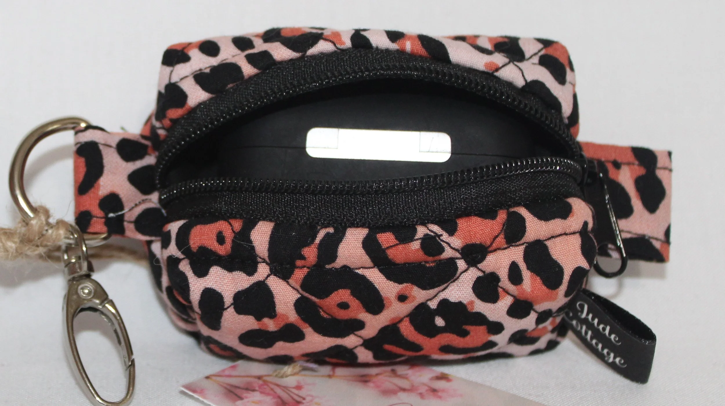 Top open view of the Mia Bag Charm featuring pink leopard print fabric shown with a set of Airpod Pro earbuds inserted for sizing reference.