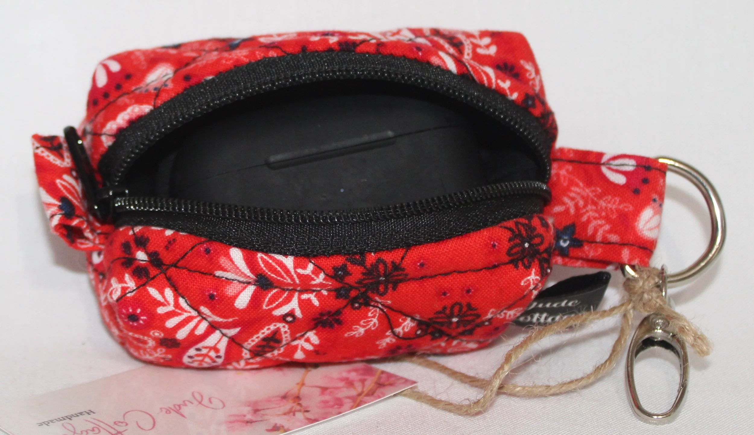 Top open view of the Freedom Red Bag Charm featuring red background with floral and paisley print fabric, shown with a J Lab earbud case inserted to demonstrate fit.