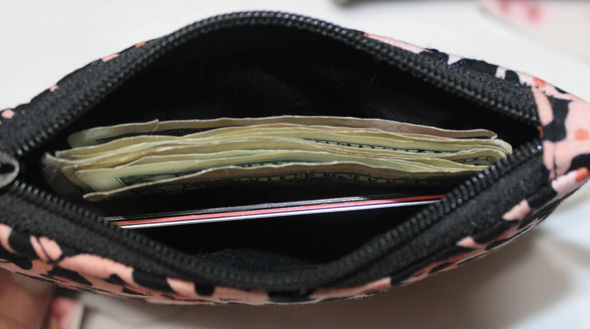 Interior view of the Mia quilted keychain wallet with cash and cards inserted and black lining.