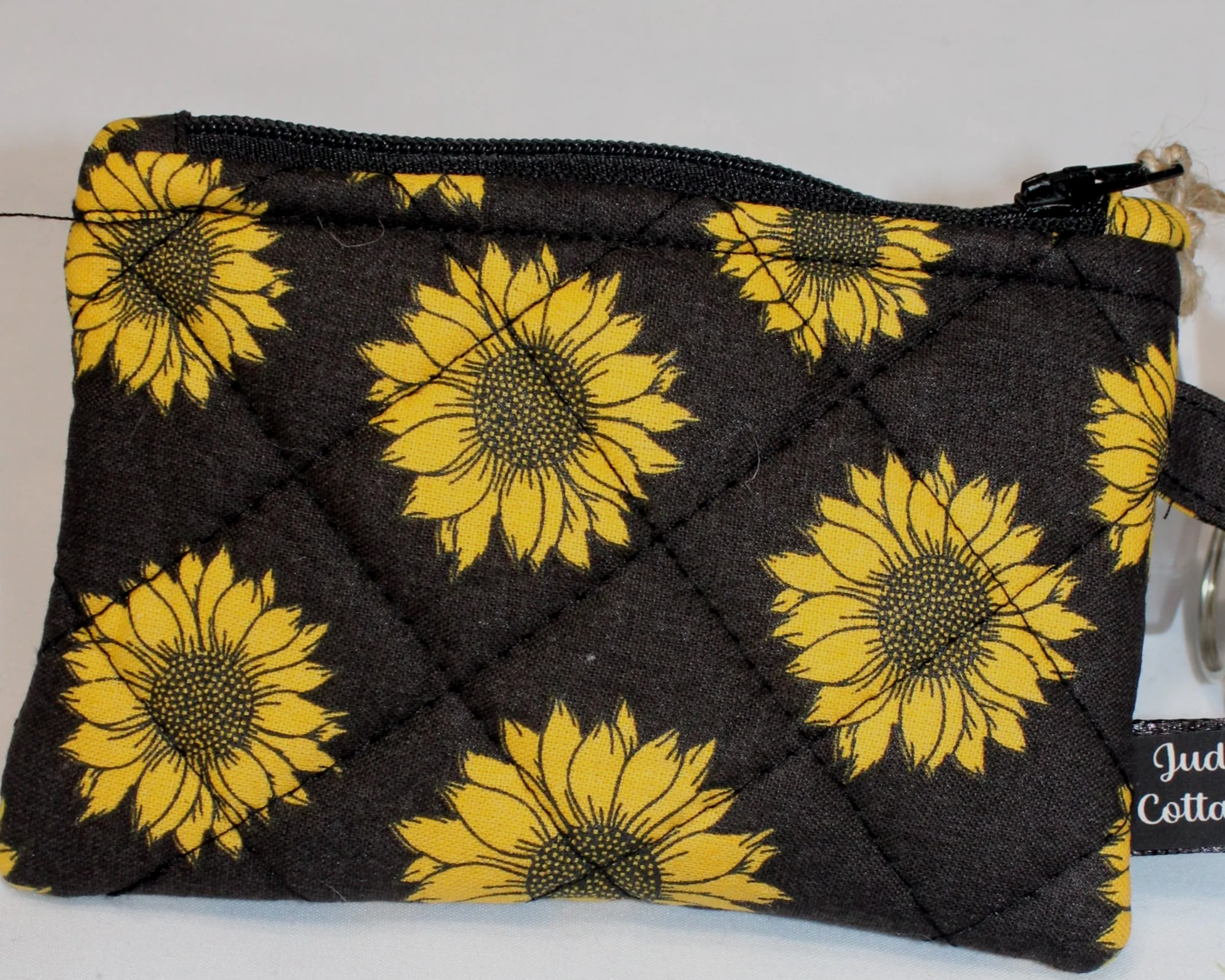 Dark quilted keychain wallet with bright sunflower pattern, zipper closure, and metal key ring.