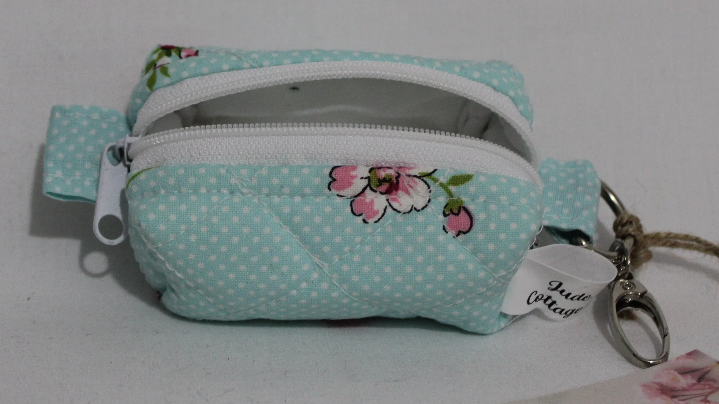 Open top view of the Blossom Bag Charm featuring a light blue polka dot fabric with pink cherry blossom print, showing white lining and zip enclosure.