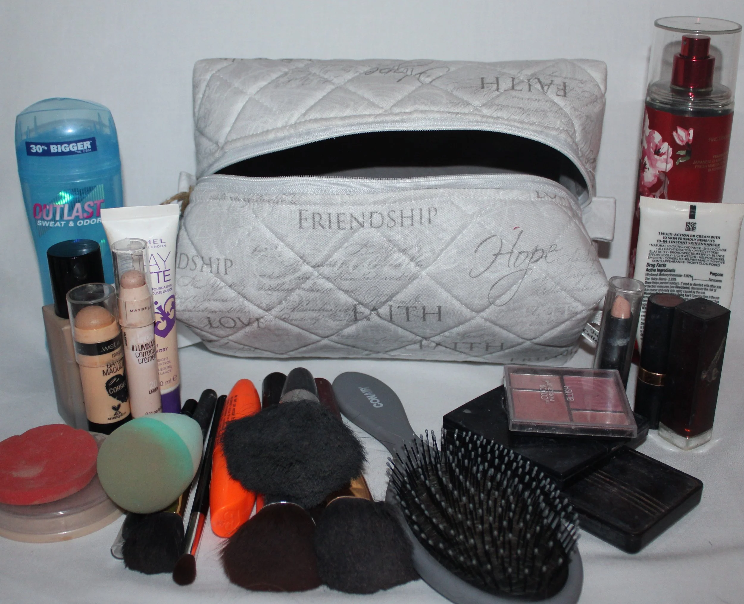 Faith Hope Love quilted cosmetic case in gray inspirational fabric shown with makeup and personal care items placed around it for scale.