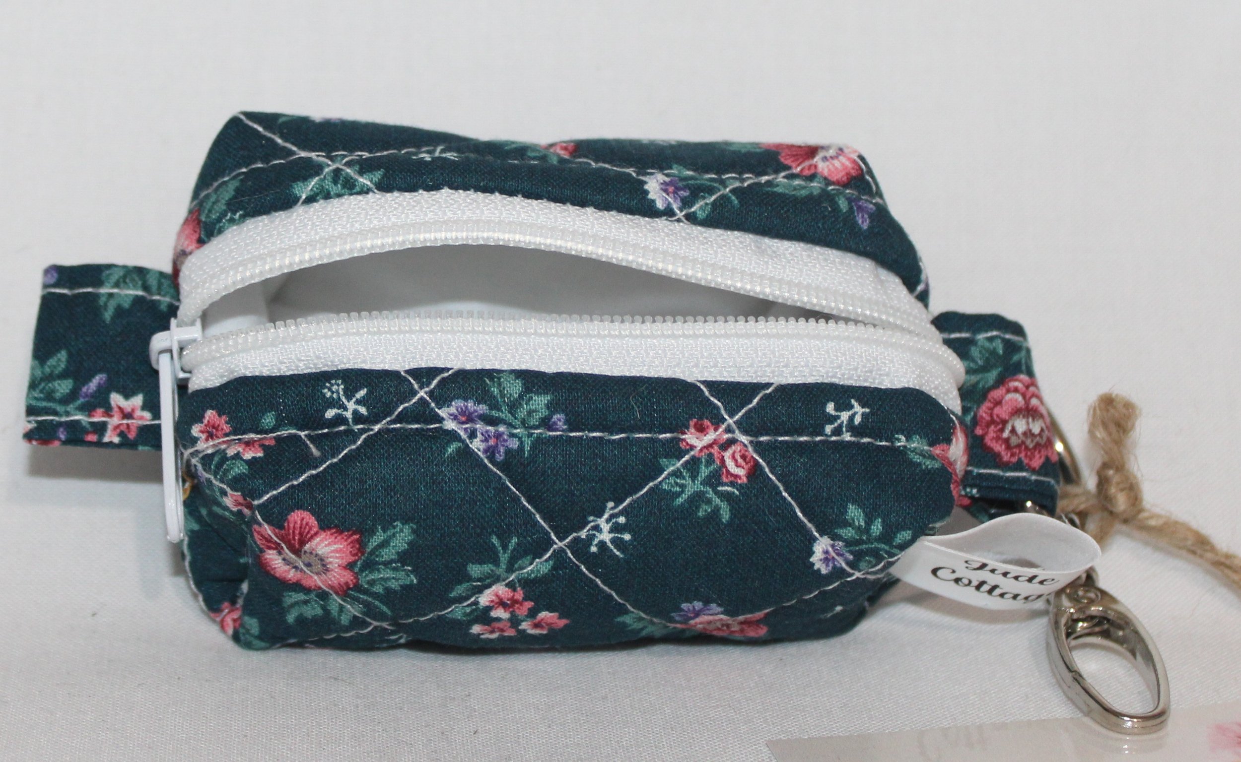 Open top view of the Eliza Bag Charm featuring a dark teal background with pink and lilac floral print showing white zip enclosure and lining.