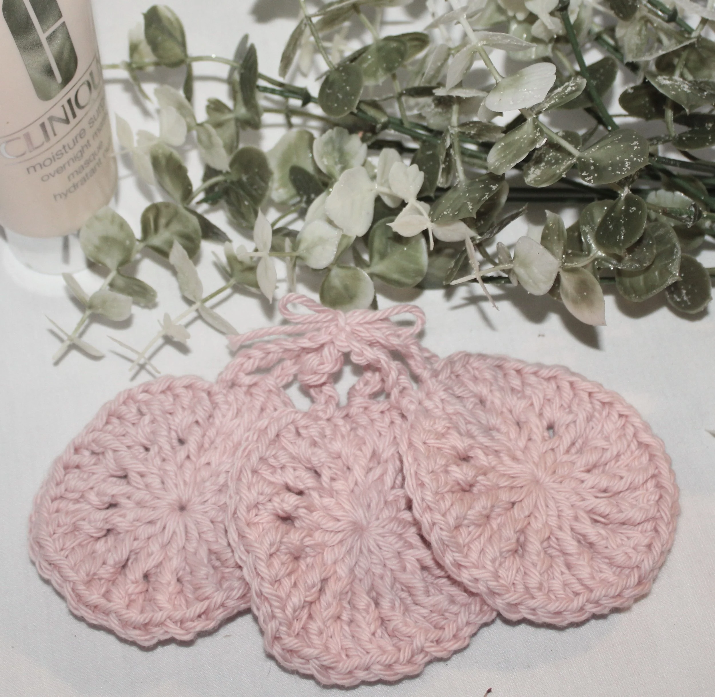 Close‑up of round crocheted pink facial scrubbies with a textured stitch pattern set of three.