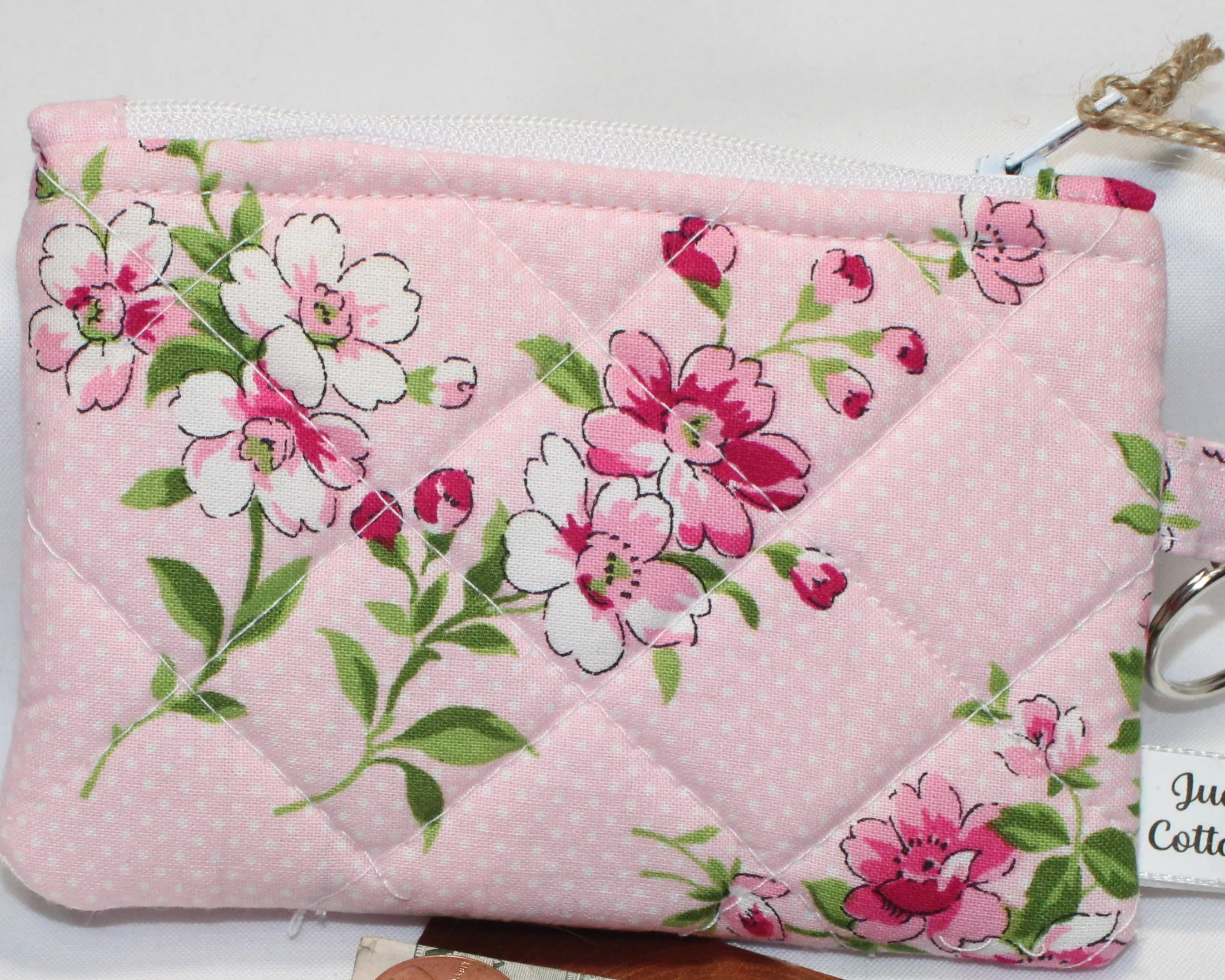 Pink quilted keychain wallet with cherry blossom floral pattern, zipper closure, and metal key ring.
