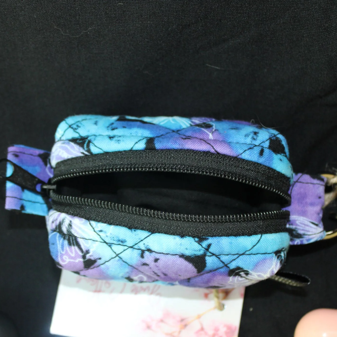 Top open zipped view of the Butterfly Mist Bag Charm showing black lining.