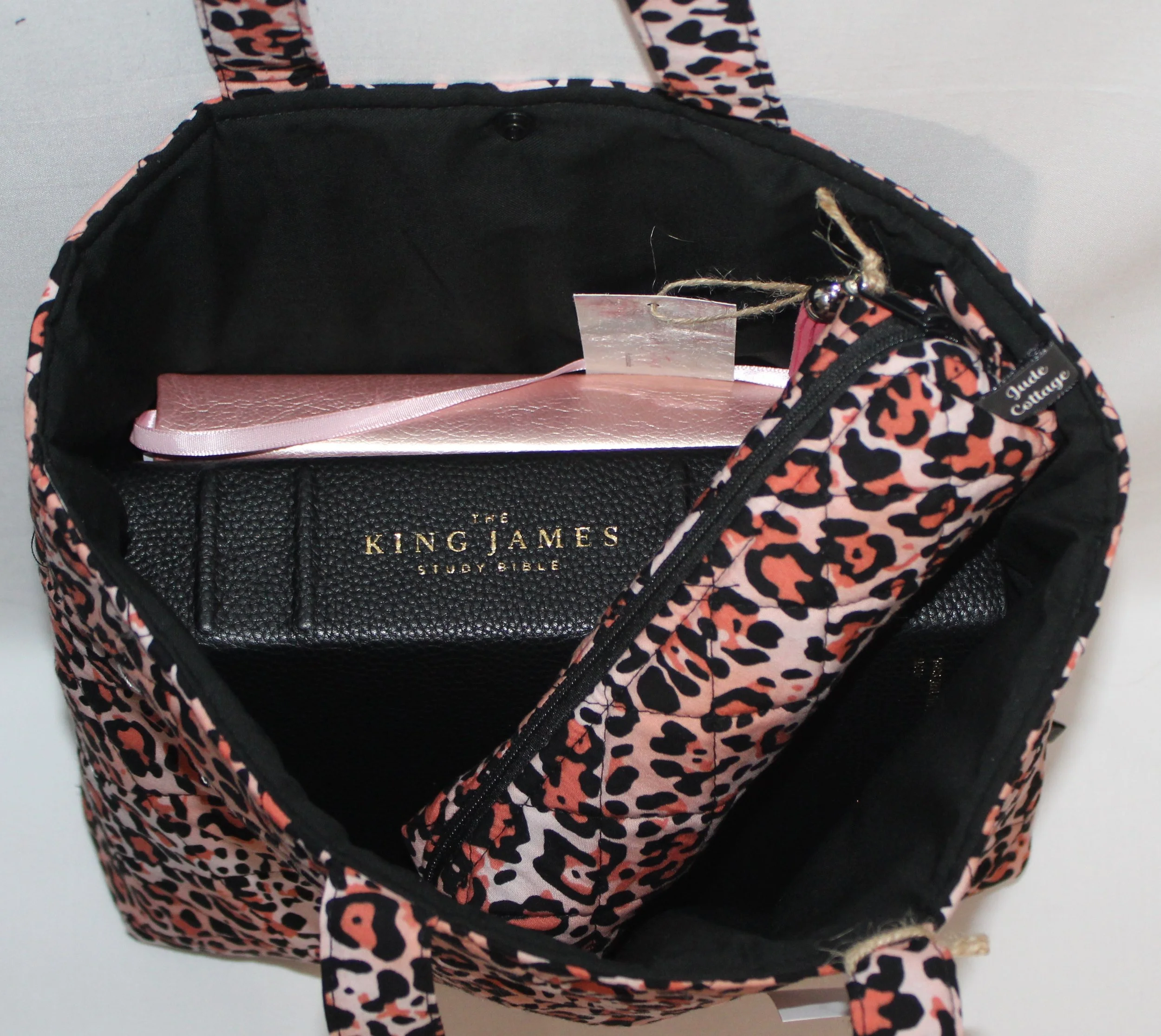 Interior view of the Mia pink cheetah‑print quilted Bible sleeve shown with a study Bible, pencil case, and devotional book inserted to illustrate size and intended use.
