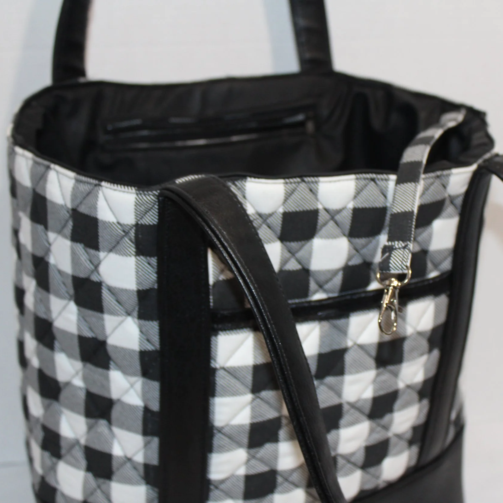 Front up close view of the Buffalo Black quilted tote bag showing a slip pocket, key strap, interior zipper, and faux leather straps.
