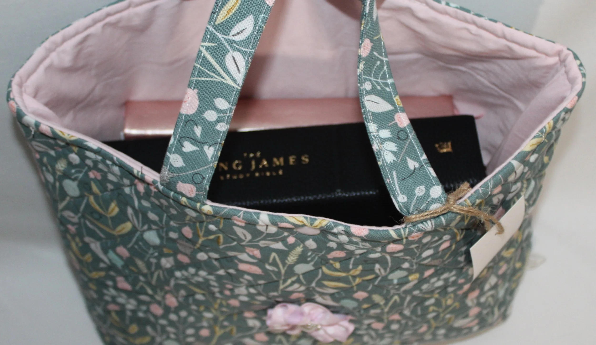 Top view of the Meadow Breeze quilted Bible sleeve featuring green floral fabric and two carry handles, shown with a Bible and notebook inserted.