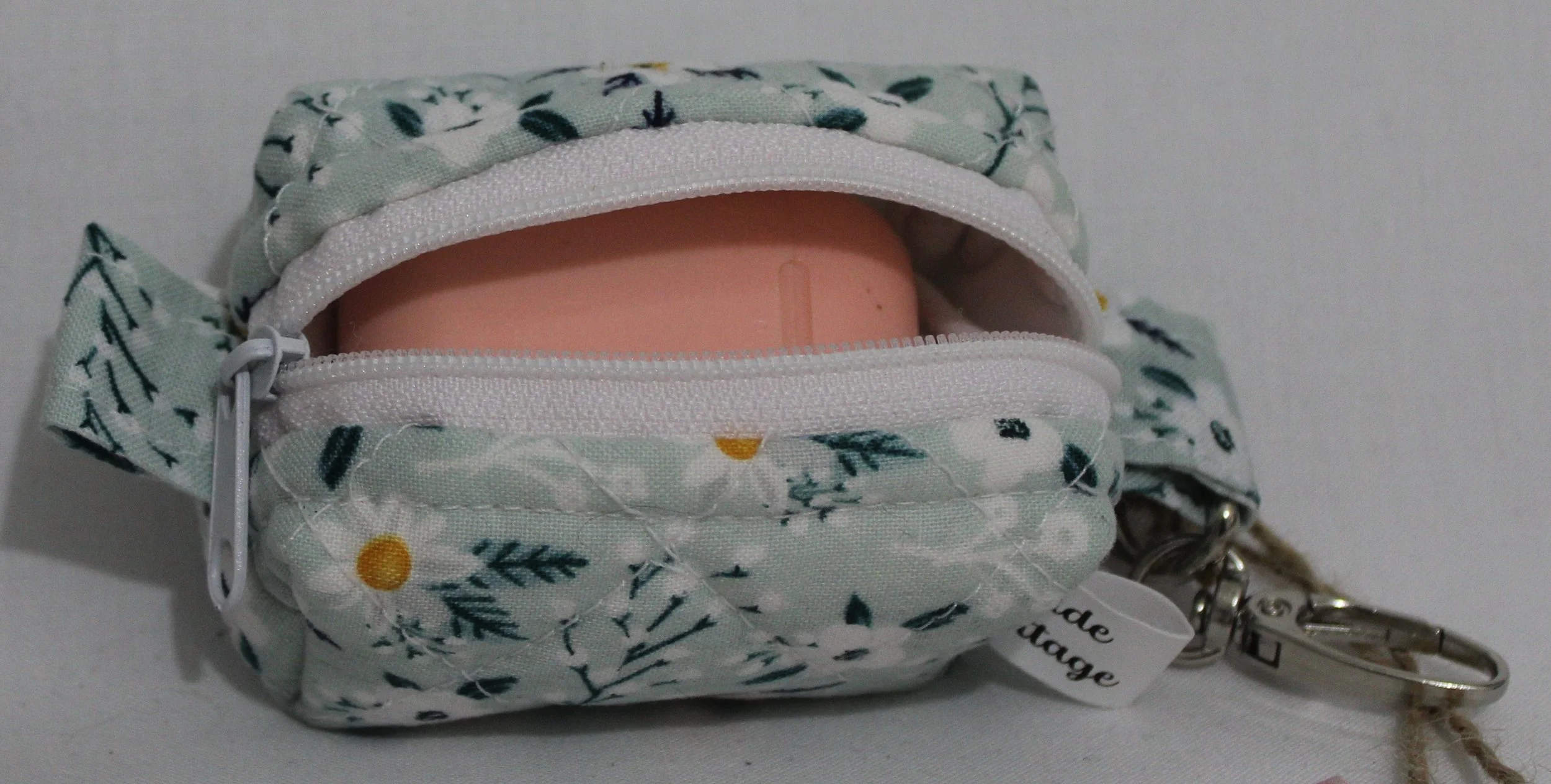 Top open view of the Vera Bag Charm shown with an Airpod case inserted for demonstration of sizing.