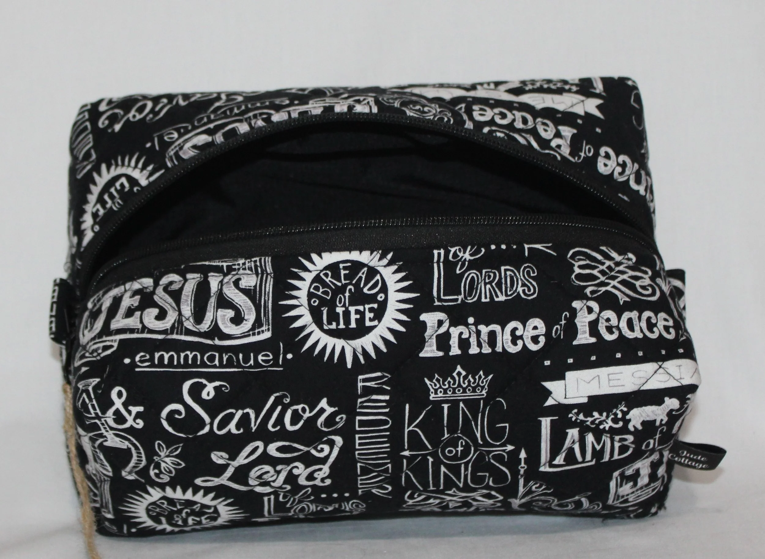 Top view of the black ‘King of Kings’ travel pouch with religious wording, shown with the zipper fully open to reveal the lined interior.