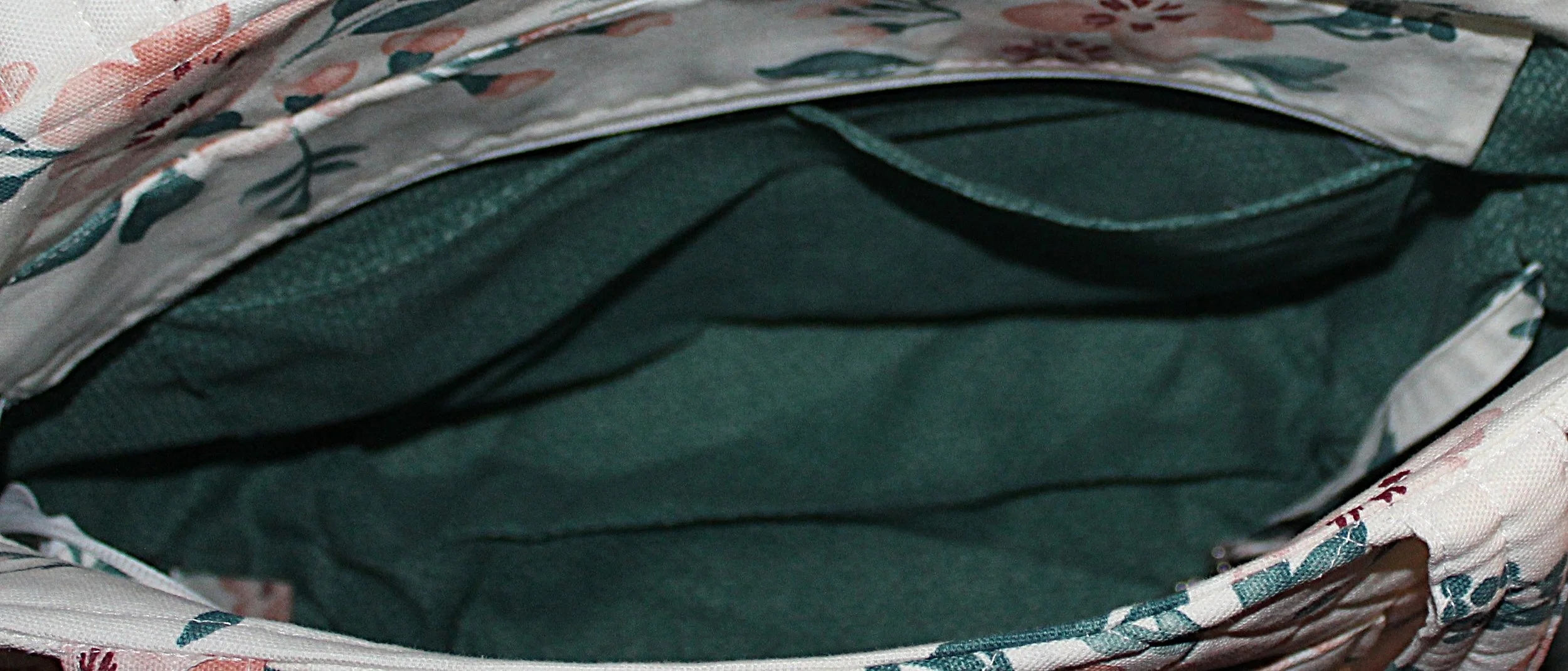 Open top view of the Odette quilted tote in white fabric with a pink floral pattern, showing the two inner slip pockets, and the recessed zipper panel folded open.