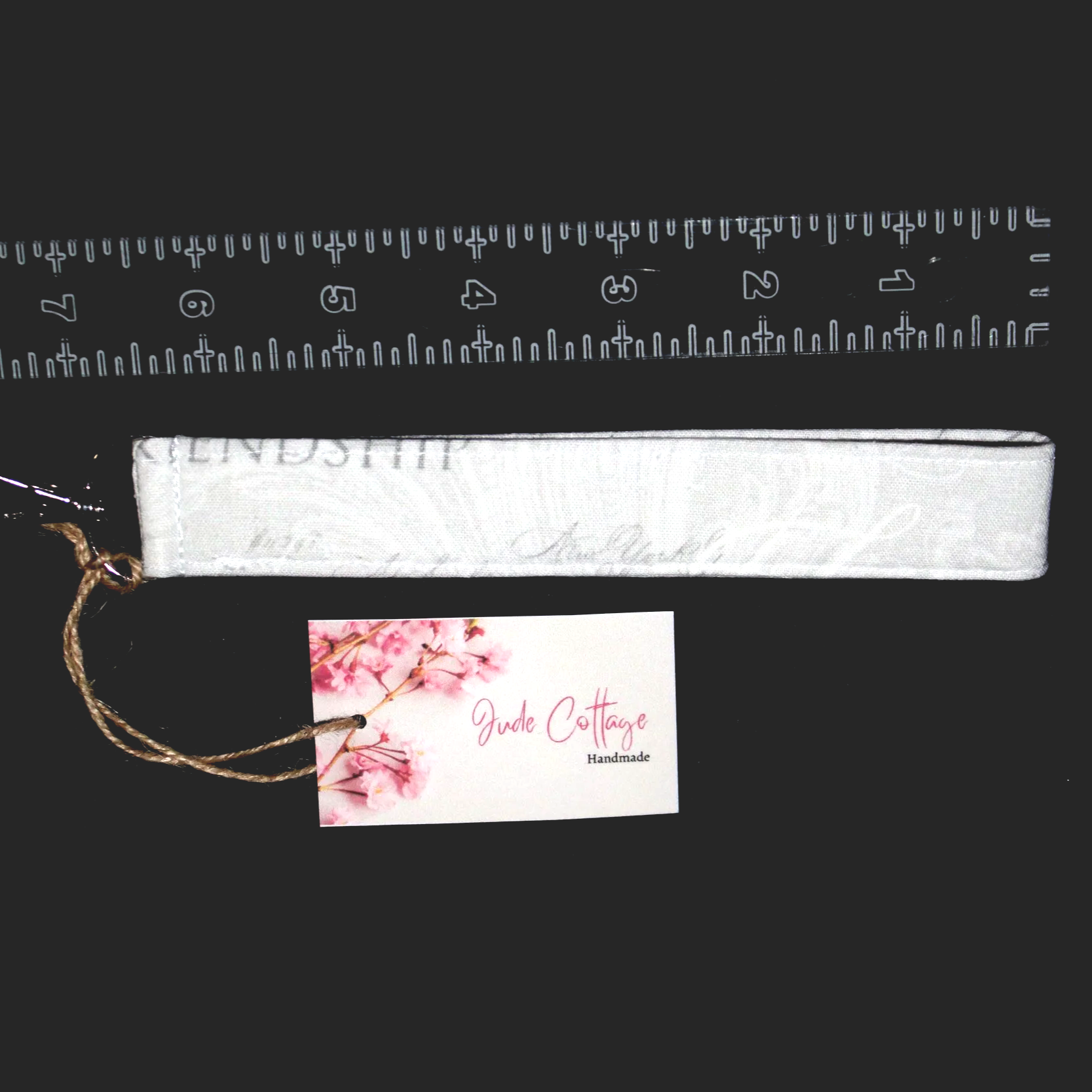 Faith Hope Love grey wristlet with a 7.5‑inch strap and metal clasp, shown against a black background with ruler to illustrate size.