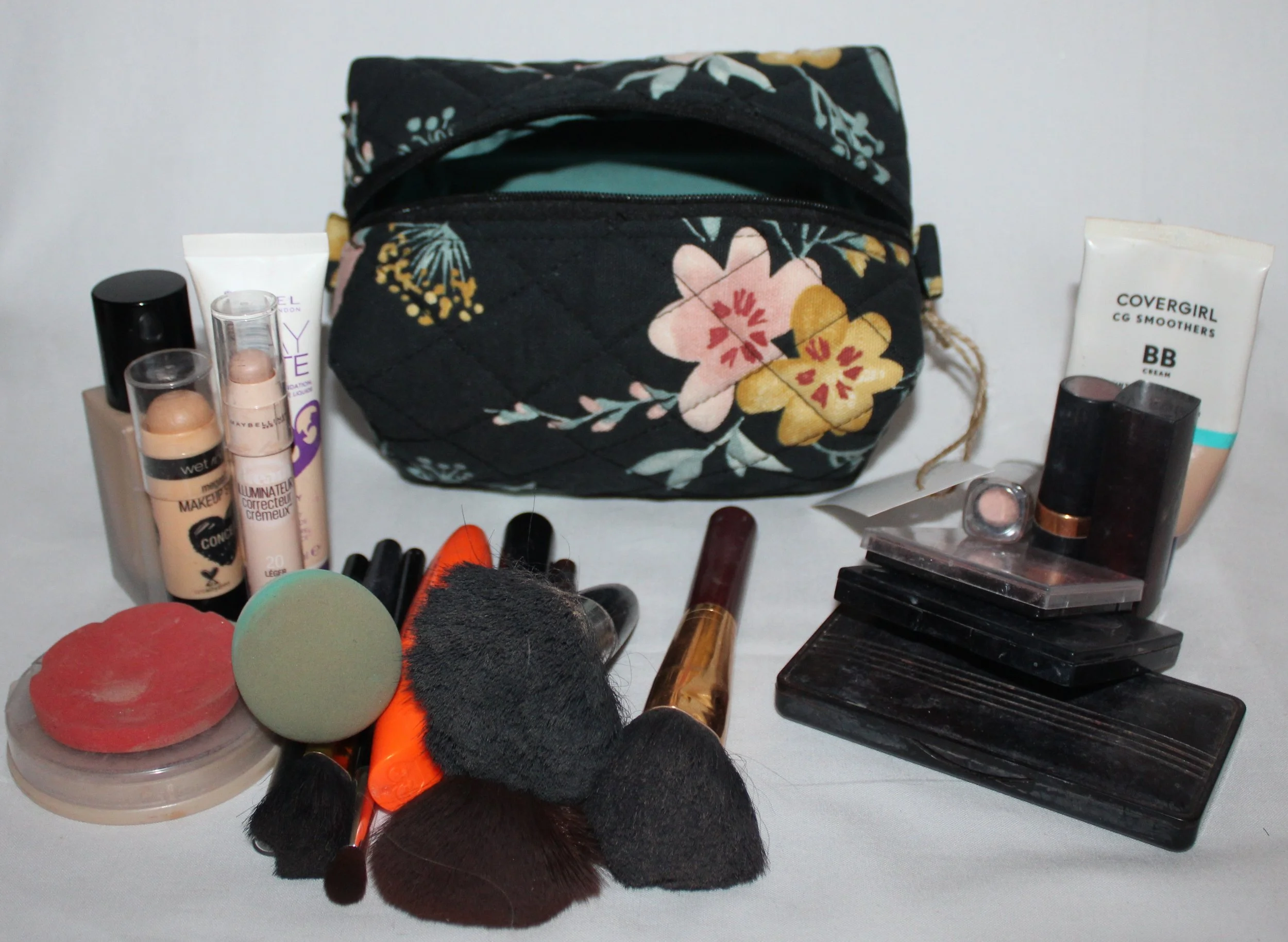 Top view of the small Twyla quilted travel pouch in floral print with the zipper open and cosmetics arranged to demonstrate size.