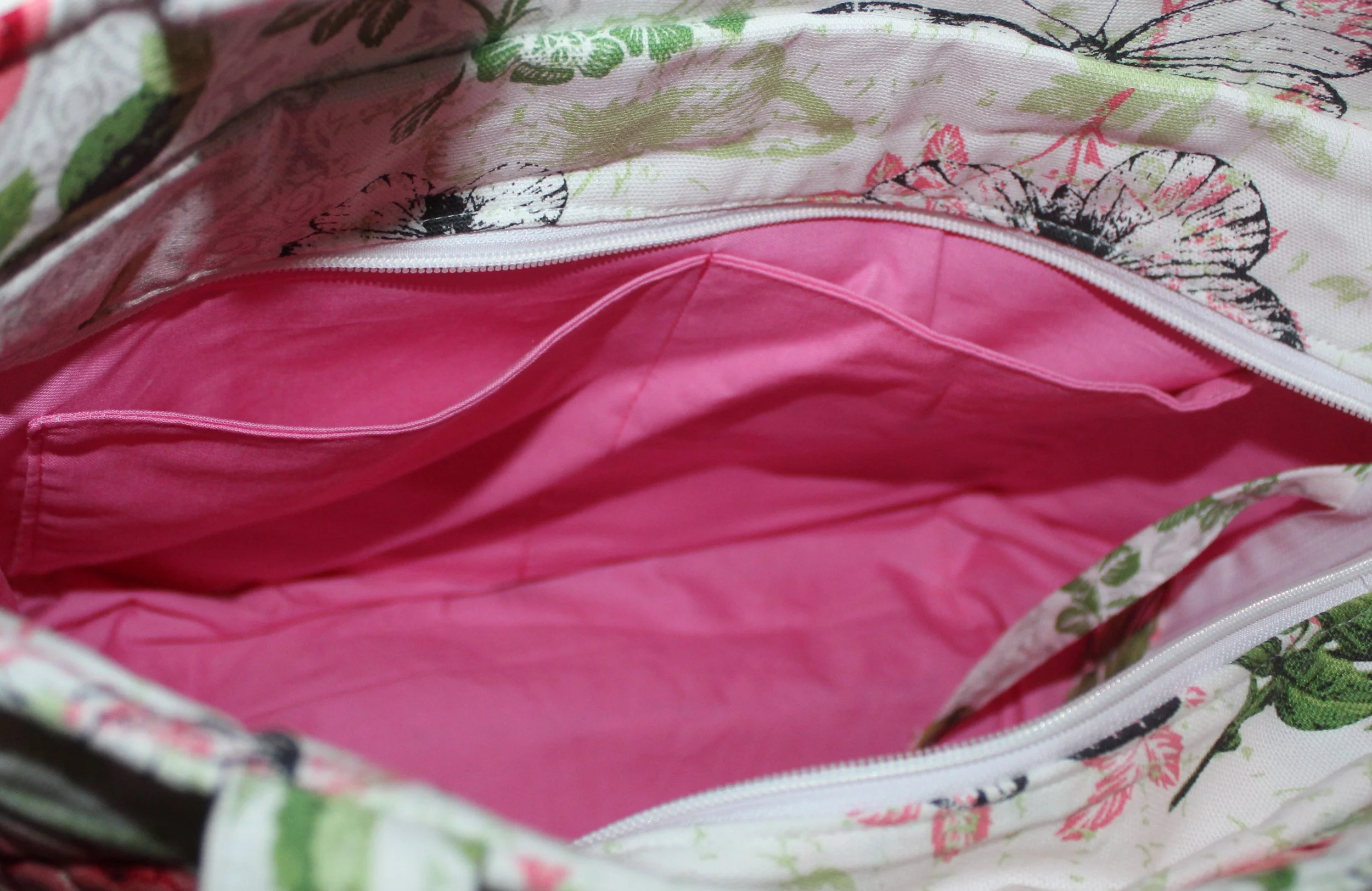 Open top view of the Colette quilted tote in white fabric with a pink floral pattern, showing the two inner slip pockets, attached key strap, and the recessed zipper panel folded open.