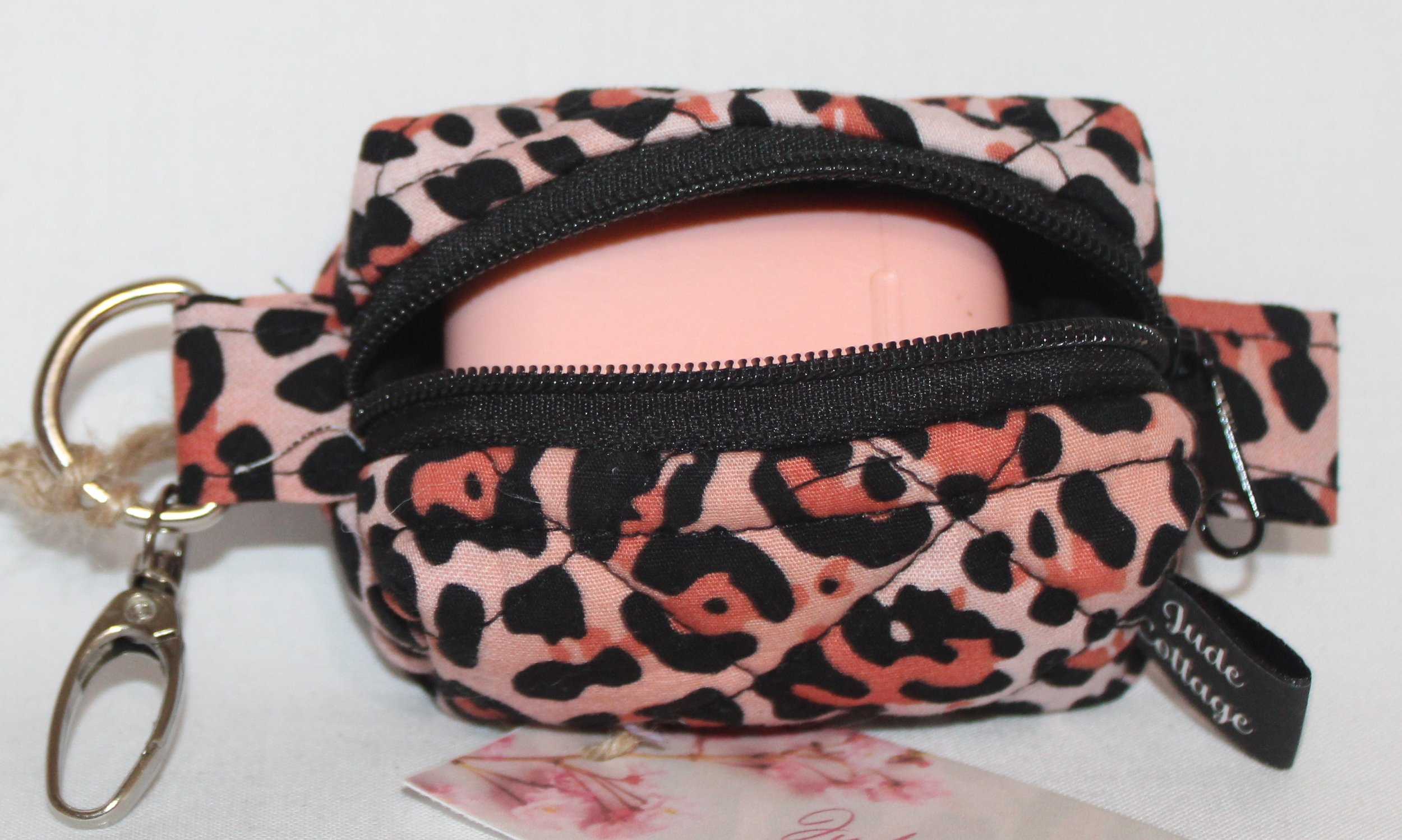 Top open view of the Mia Bag Charm featuring pink leopard print fabric shown with a set of Airpod earbuds inserted for sizing reference.