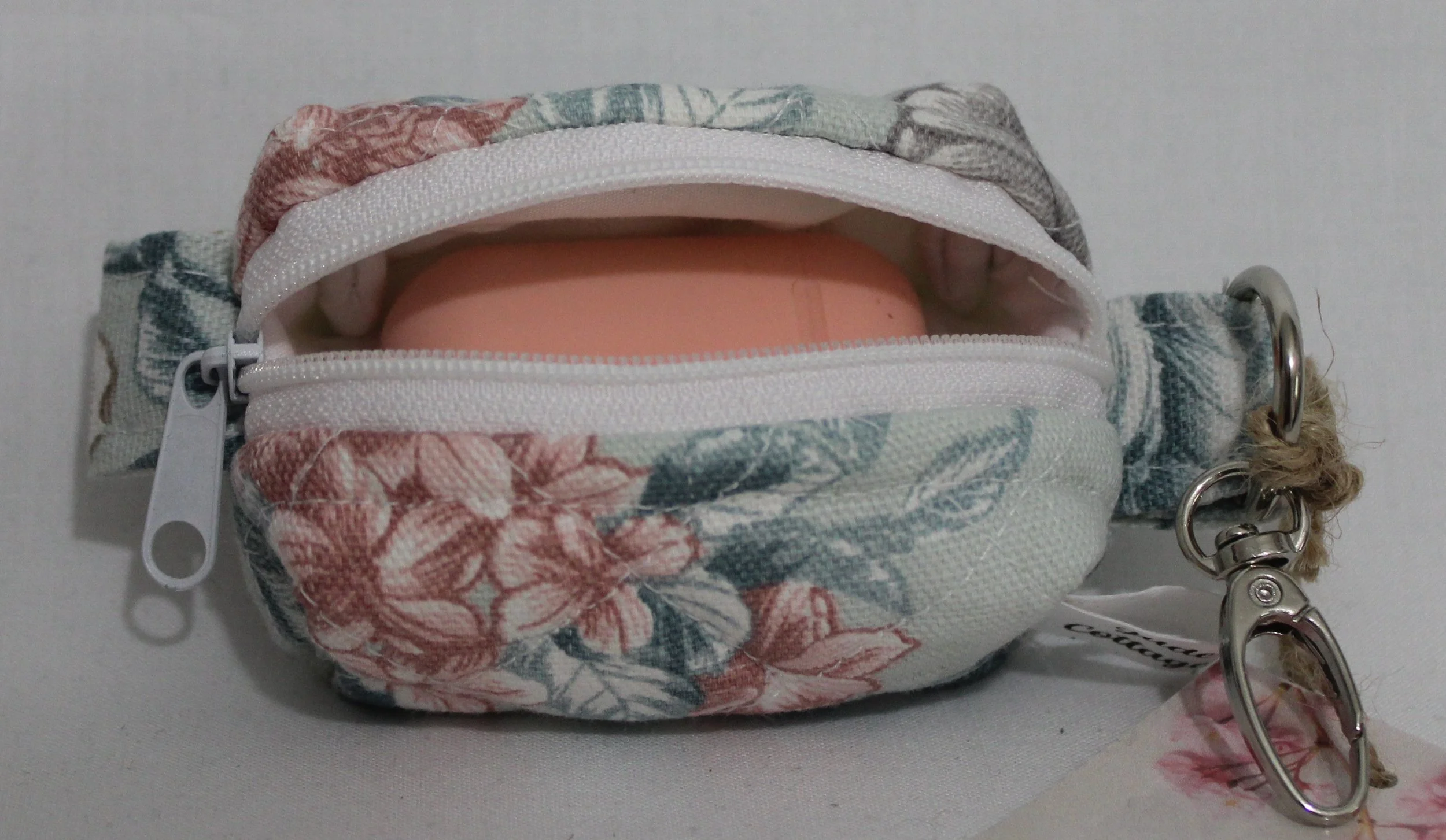 Open top view of the Joelle Bag Charm showing zip enclosure and an Airpod earbud case inserted to size reference.