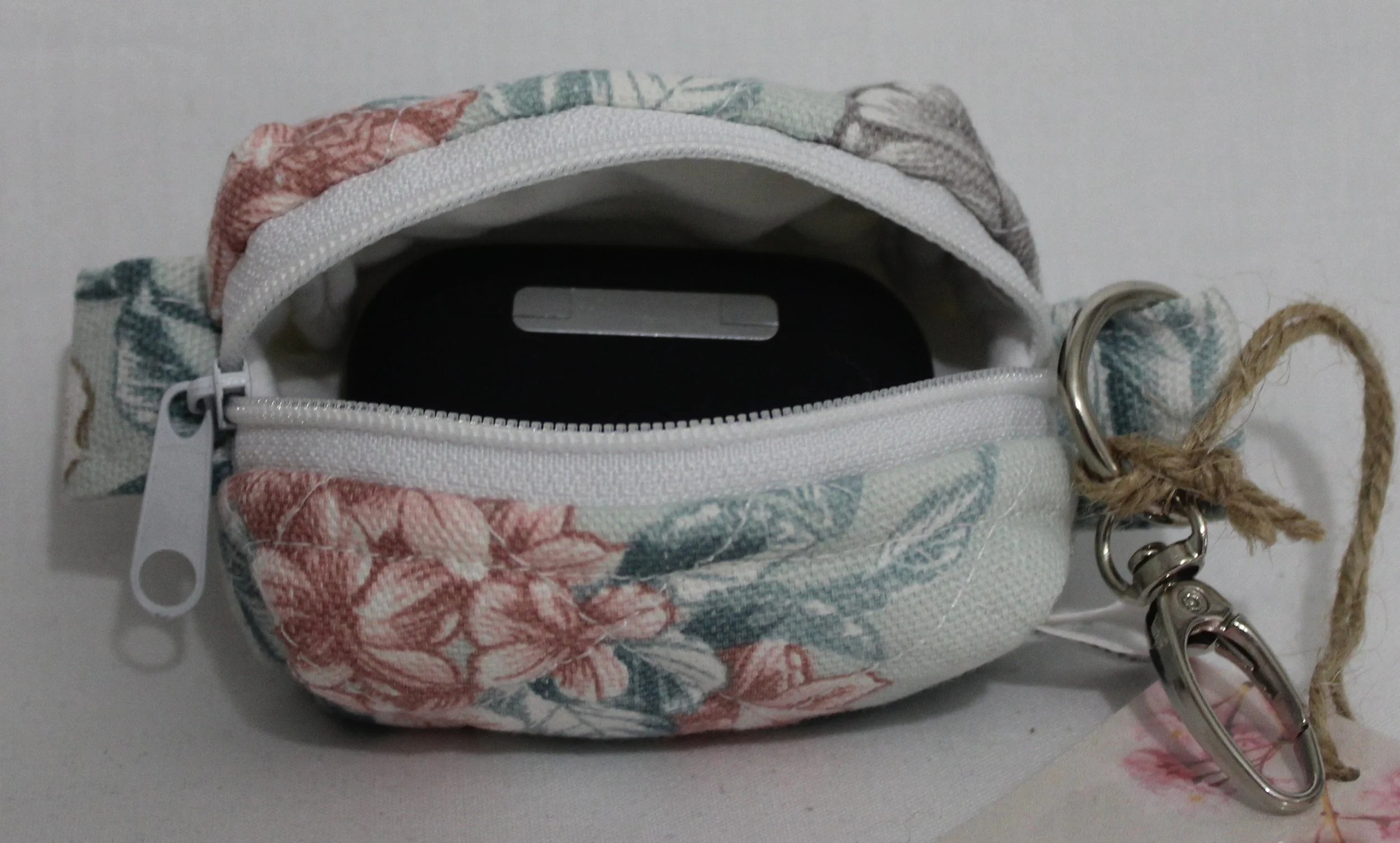 Open top view of the Joelle Bag Charm showing zip enclosure and an Airpod Pro earbud case inserted to size reference.