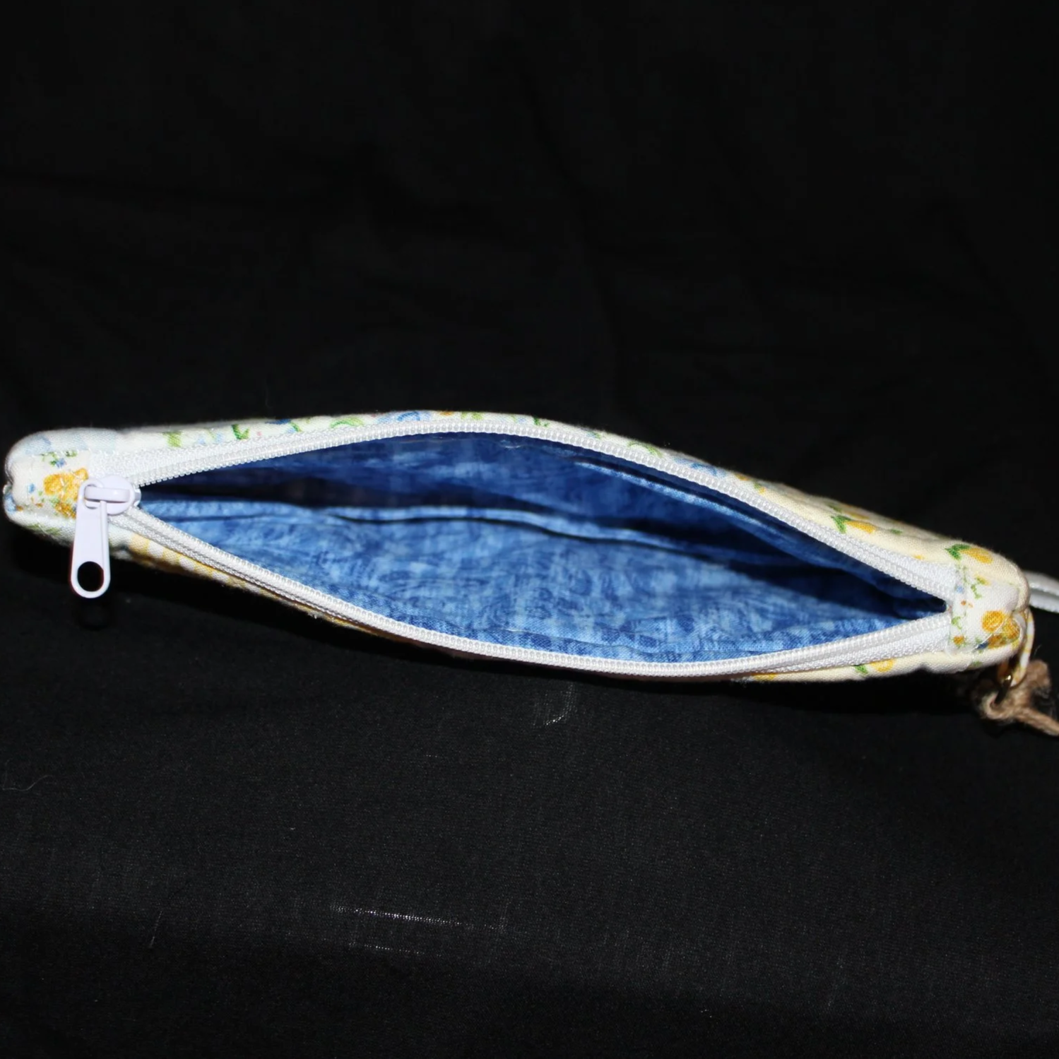 Top open view of the Annalee Large Keychain wallet featuring yellow, green, blue, and white patchwork fabric, showing white zip closure and blue lining fabric.