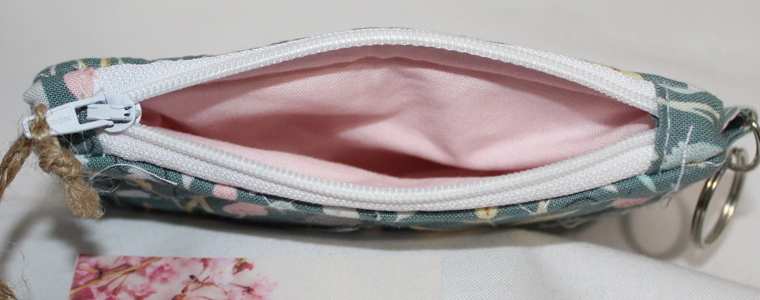 Top view soft green quilted keychain wallet with meadow floral pattern, zipper closure, and metal key ring.