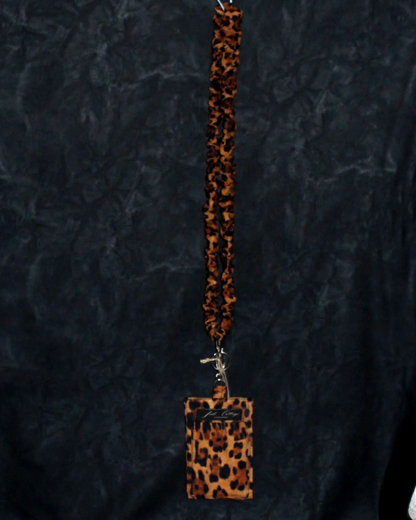 Hanging view of the Lyra Scrunch Lanyard with Badge Holder featuring a bold leopard print pattern.