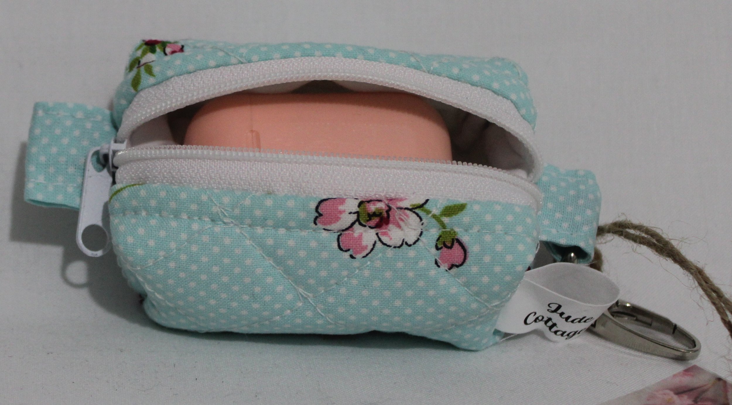 Top open view of the Blossom Bag Charm featuring a light blue polka dot fabric with pink cherry blossom print shown with an Airpod earbud case inserted for sizing reference.