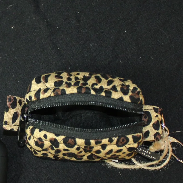 Top unzipped view of the Sahara Bag Charm featuring cheetah print fabric and showing black lining.
