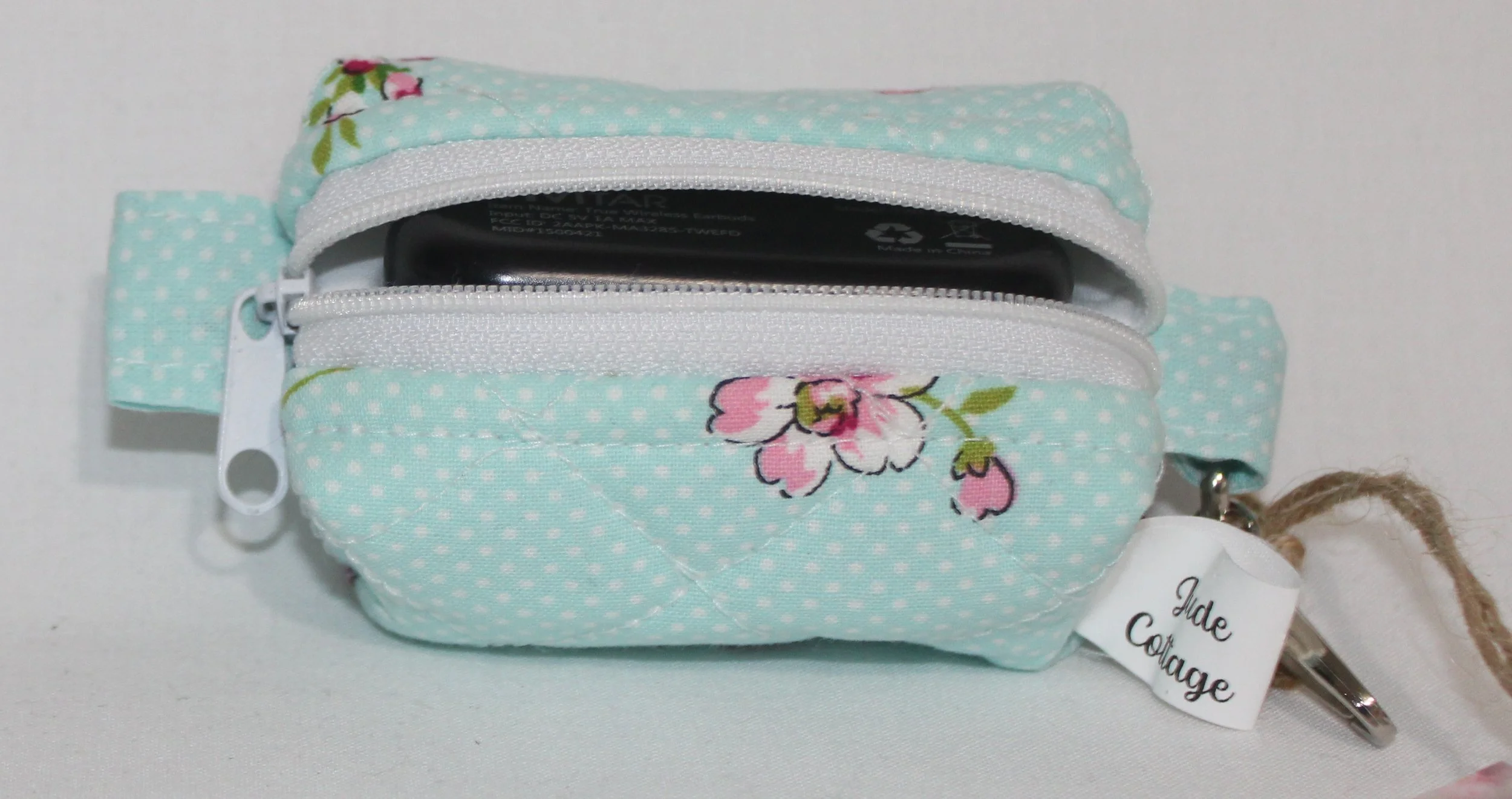 Top open view of the Blossom Bag Charm featuring a light blue polka dot fabric with pink cherry blossom print shown with a J Lab earbud case inserted for sizing reference.