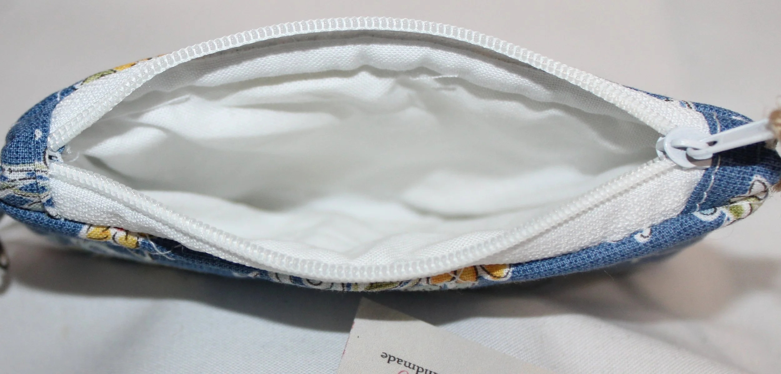 Top view of Liberty Blue quilted keychain wallet showing the white lining and zip closure.