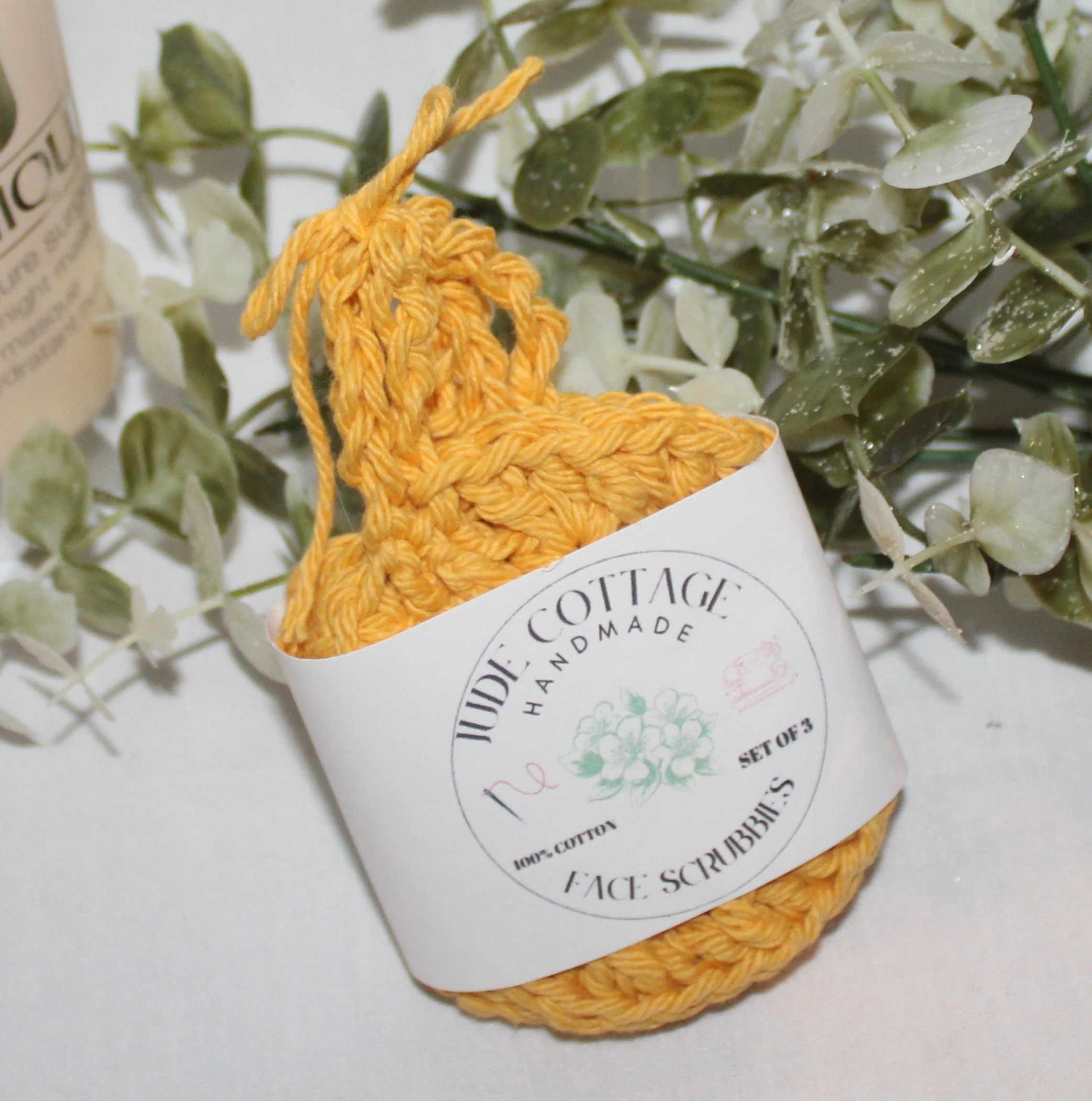Close‑up of round crocheted dandelion facial scrubbies with a textured stitch pattern shown with label.