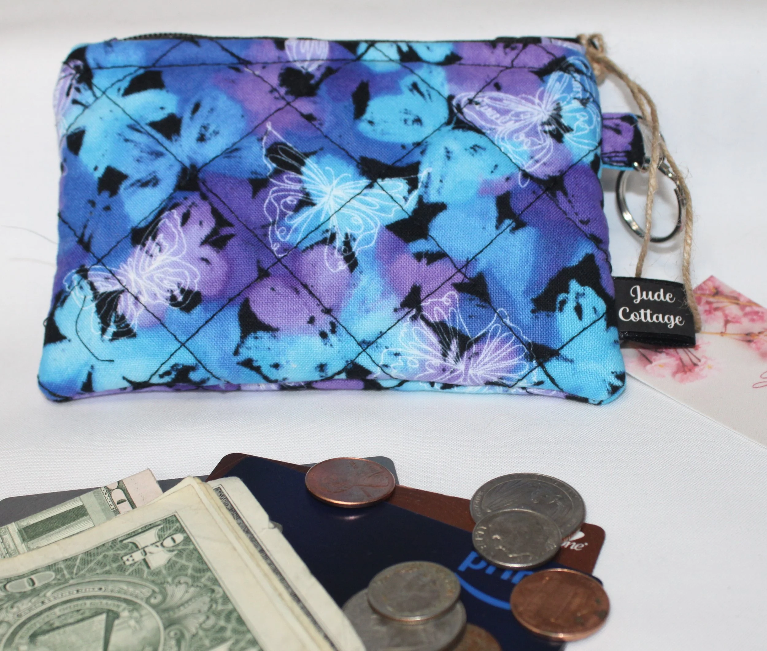 Quilted keychain wallet with mist‑toned butterfly pattern, zipper closure, and metal key ring.