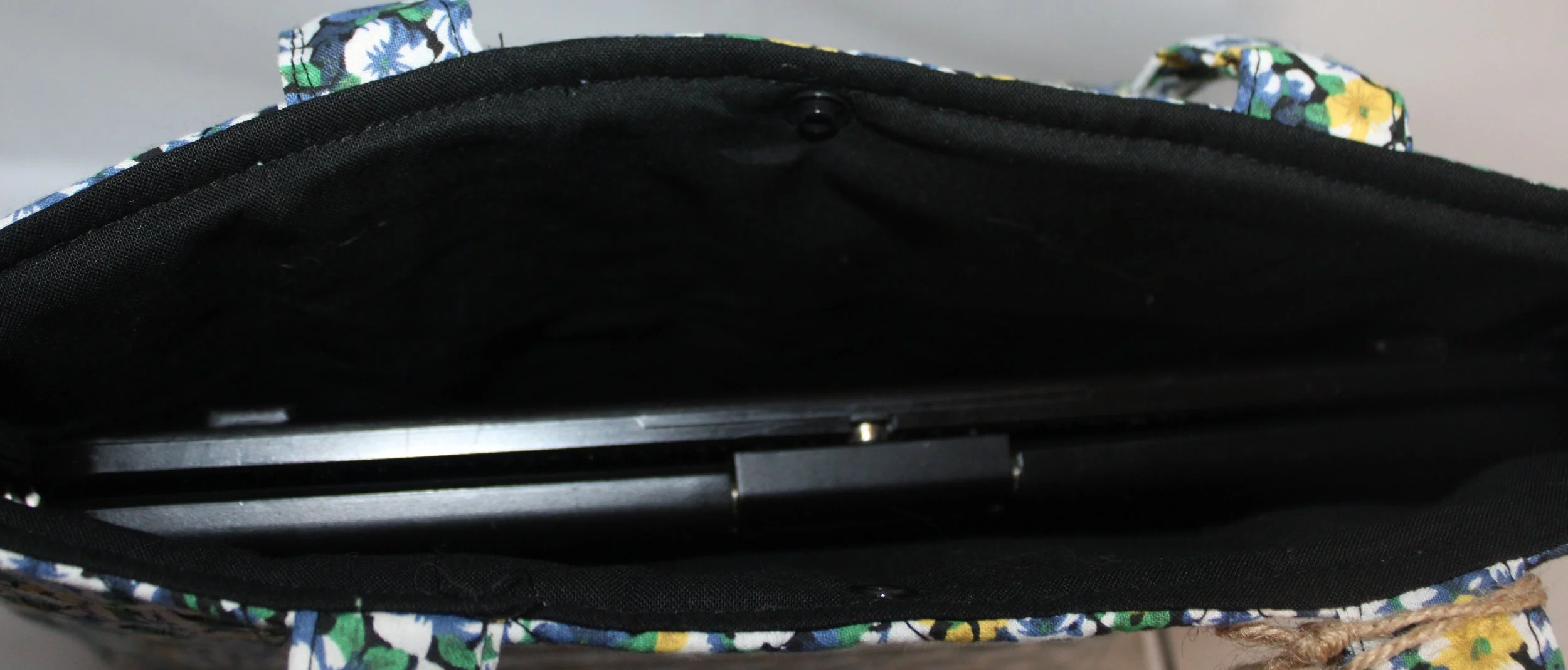 Top view of the Luna quilted tablet and book sleeve with blue, white, and yellow flowers, two carry handles, with tablet inserted.