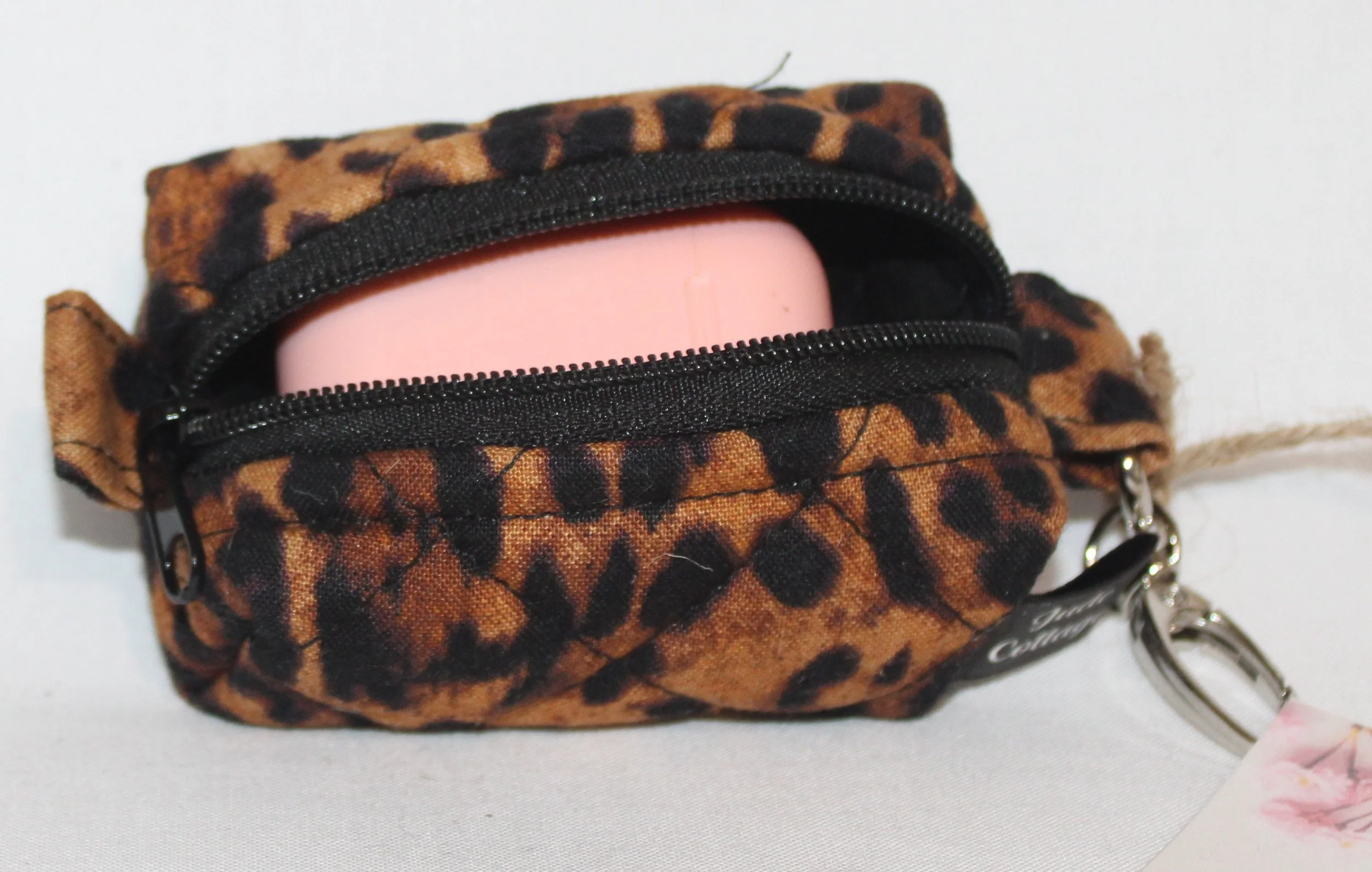 Top open view of the Lyra Bag Charm featuring a leopard print fabric and shown with an Airpod case inserted for sizing reference.
