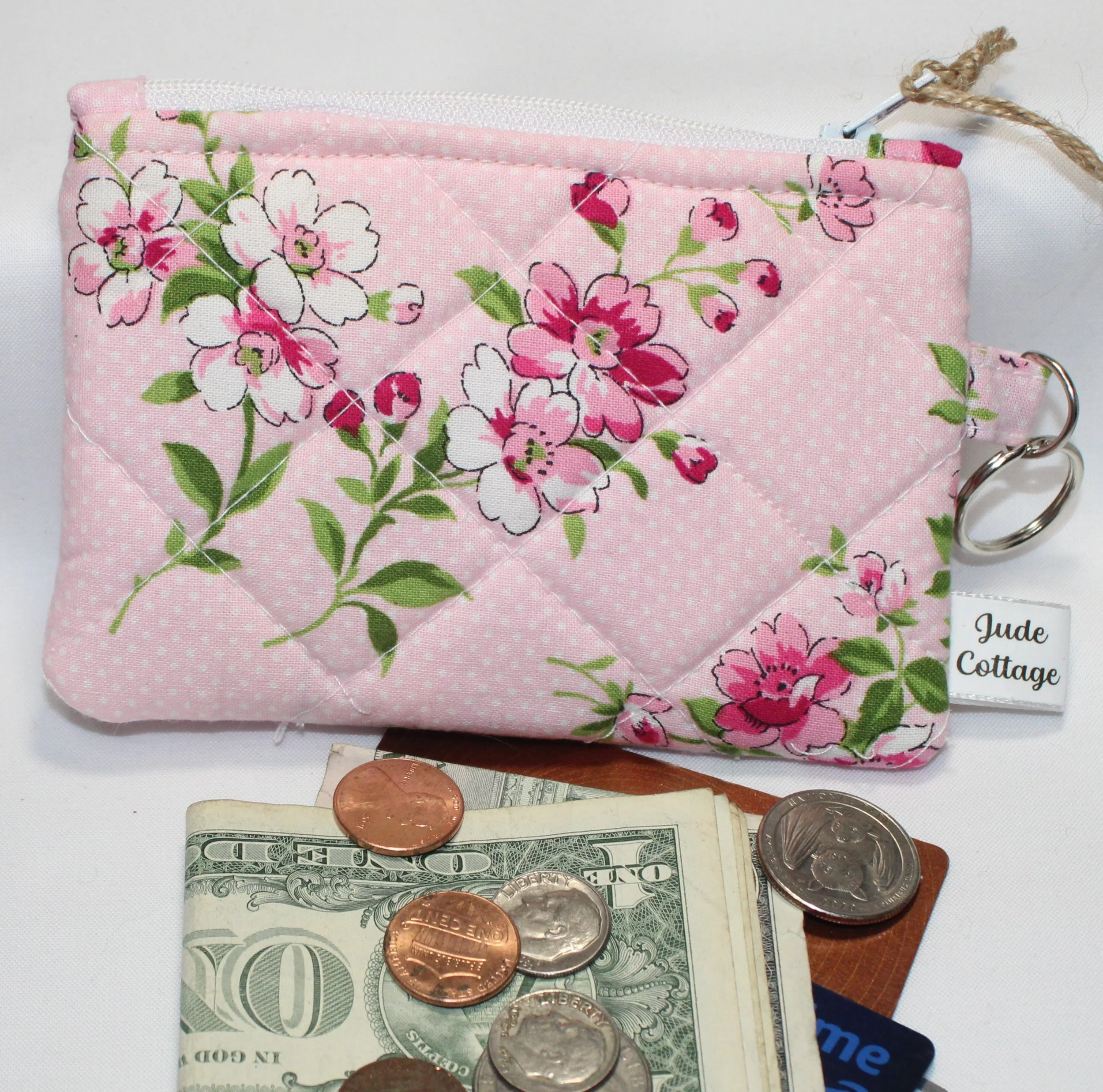 Pink quilted keychain wallet with cherry blossom floral pattern, zipper closure, and metal key ring.