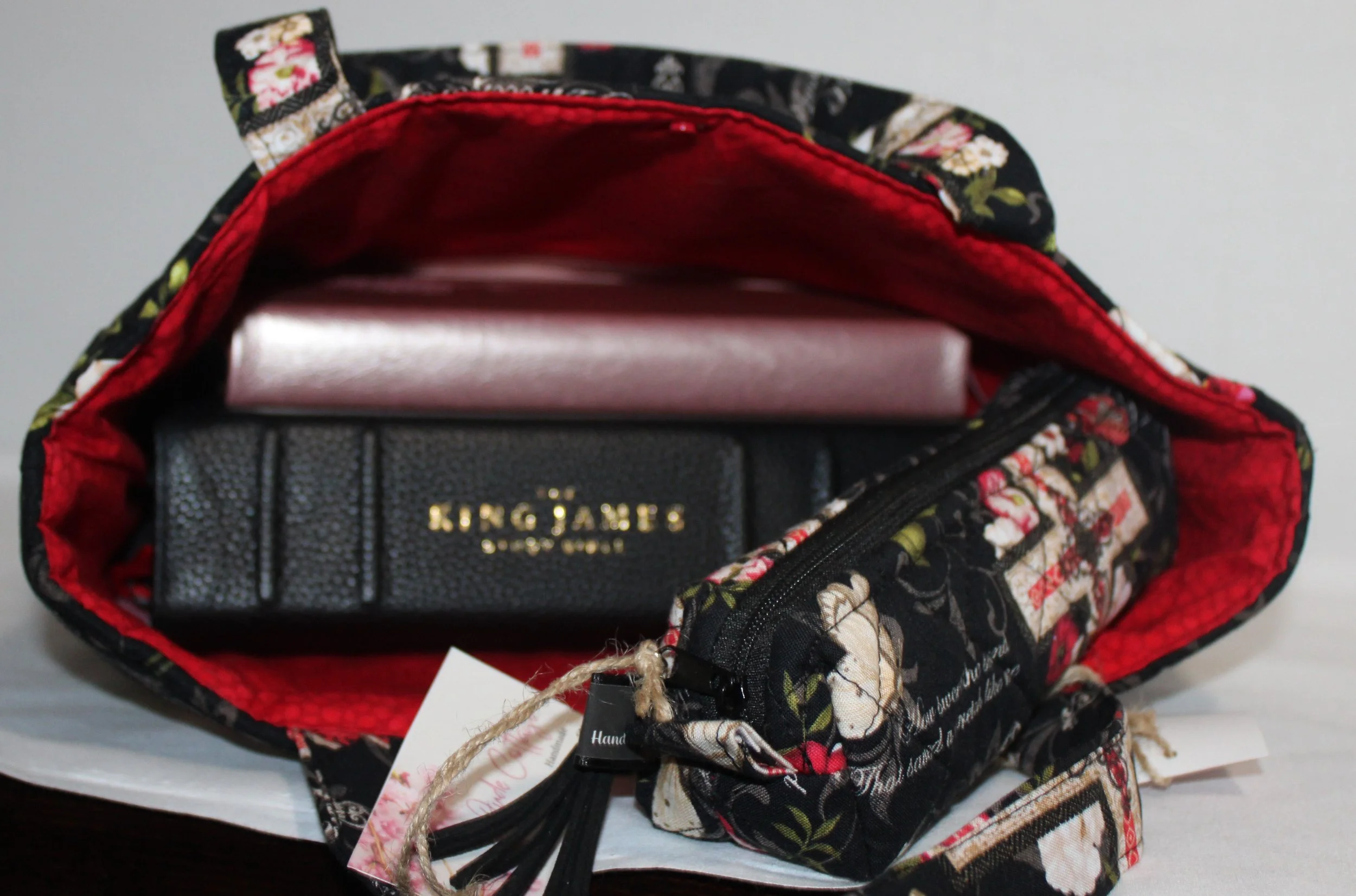 Top view of the Amazing Grace quilted Bible sleeve with two carry handles and a snap closure, shown holding an open Bible, a small notebook, and a pencil case.