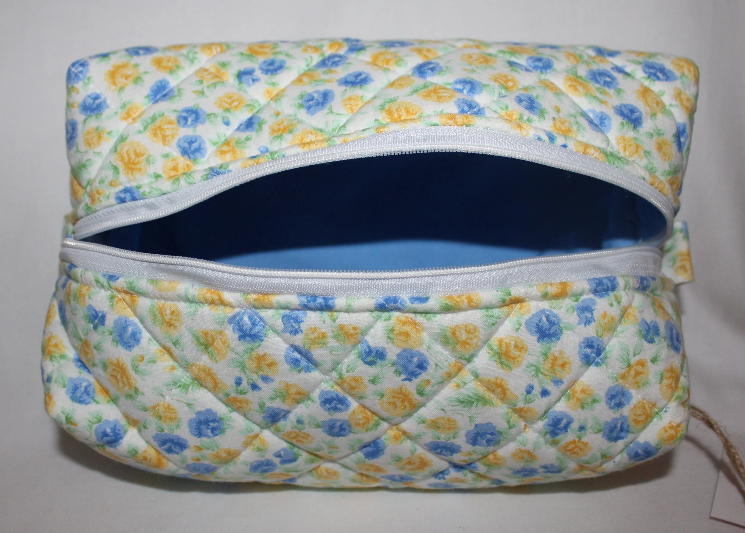 Top view of the Melody quilted travel pouch with the zipper open, showing the empty blue interior.