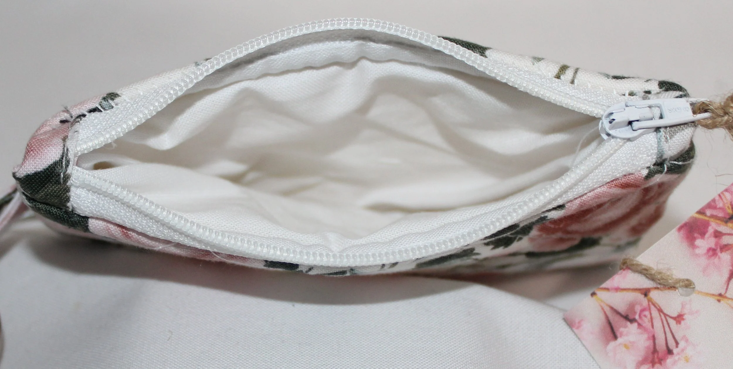 Top view quilted keychain wallet with rose garden floral pattern, zipper closure, and metal key ring showing white lining.