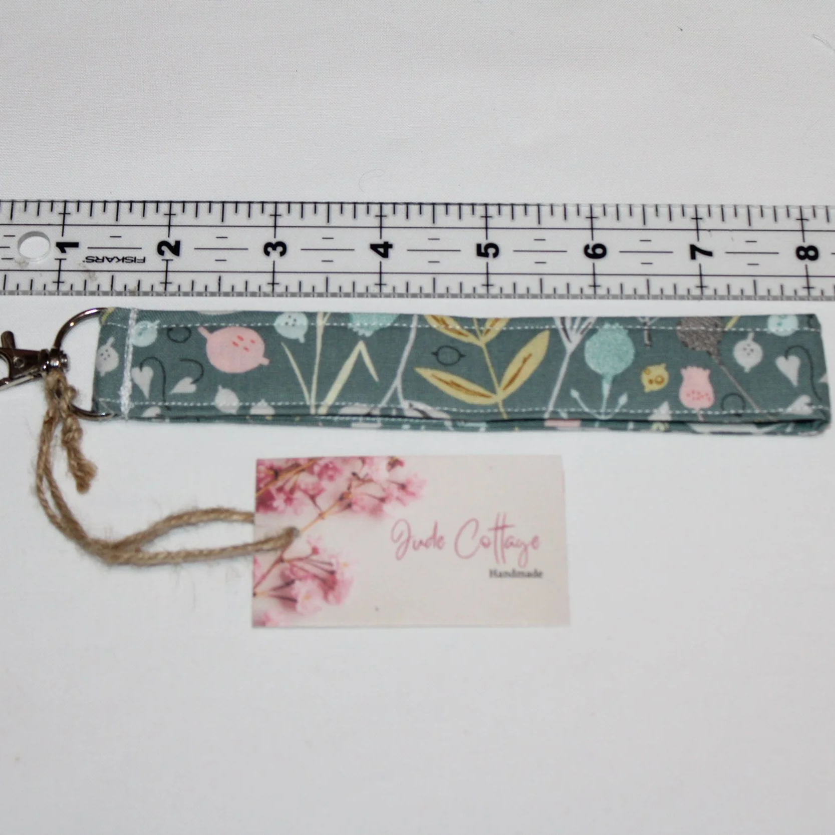 Close up view of the Meadow Breeze, with a soft green quilted wristlet with meadow floral pattern, shown next to a ruler to demonstrate length.