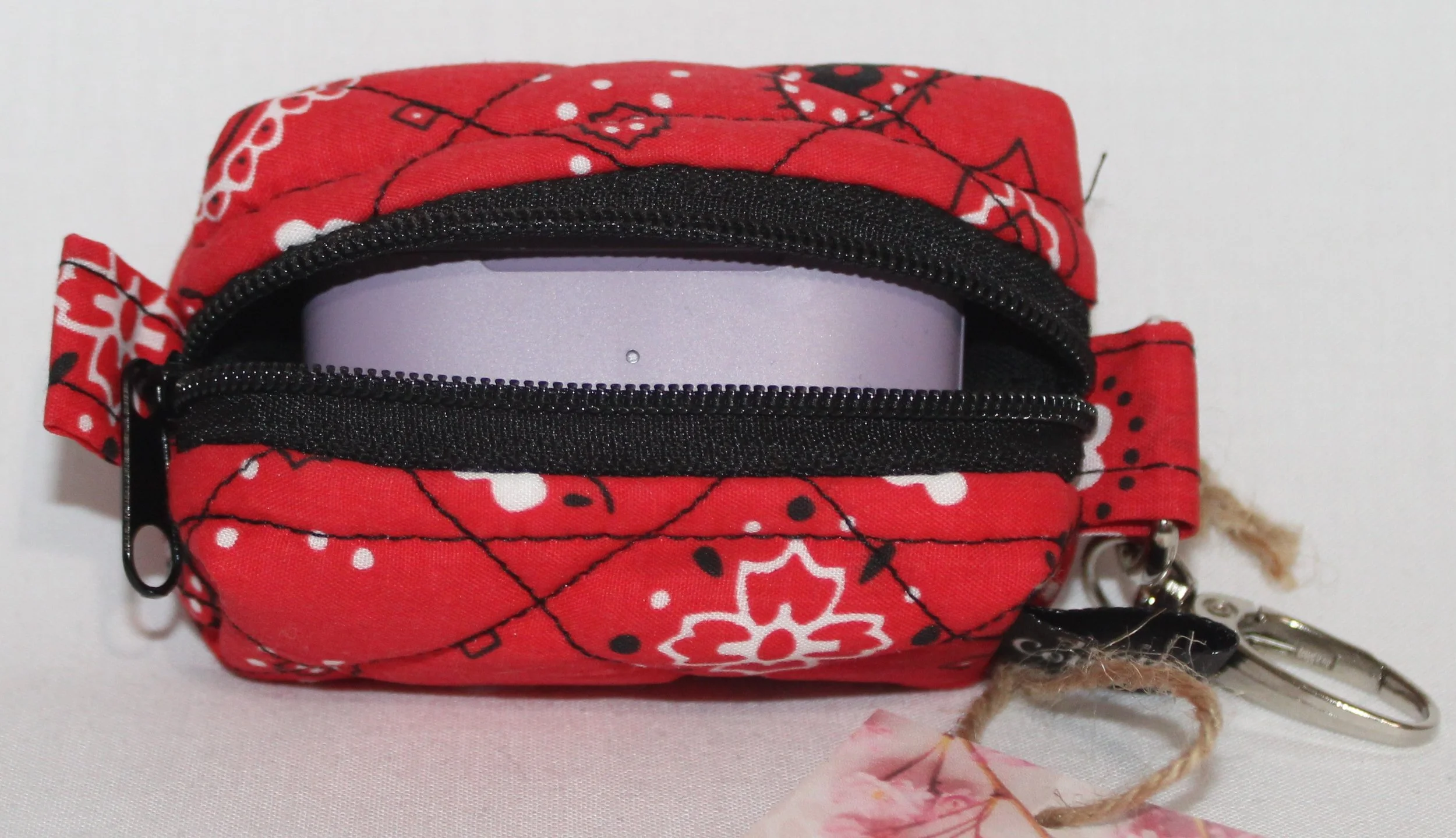 Top open view of the Red Bandana Bag Charm showing bandana print fabric with a set of J Lab earbuds inserted for size reference.