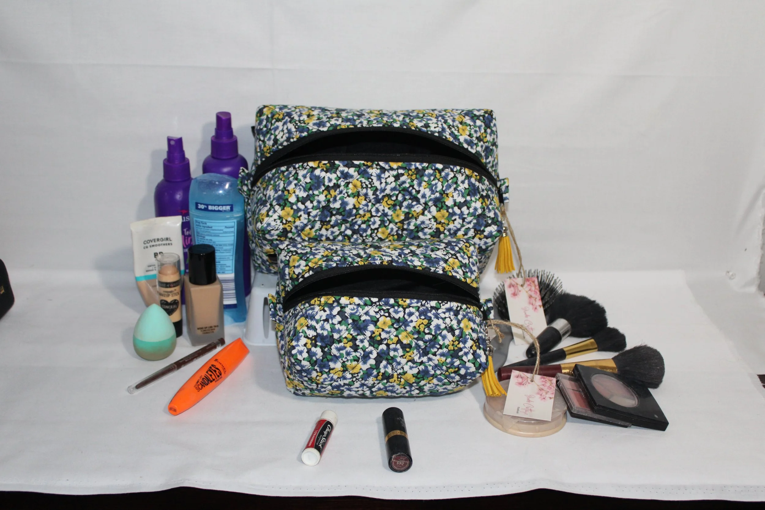 Luna large and small quilted travel pouches displayed with assorted hygiene and beauty products to show size.