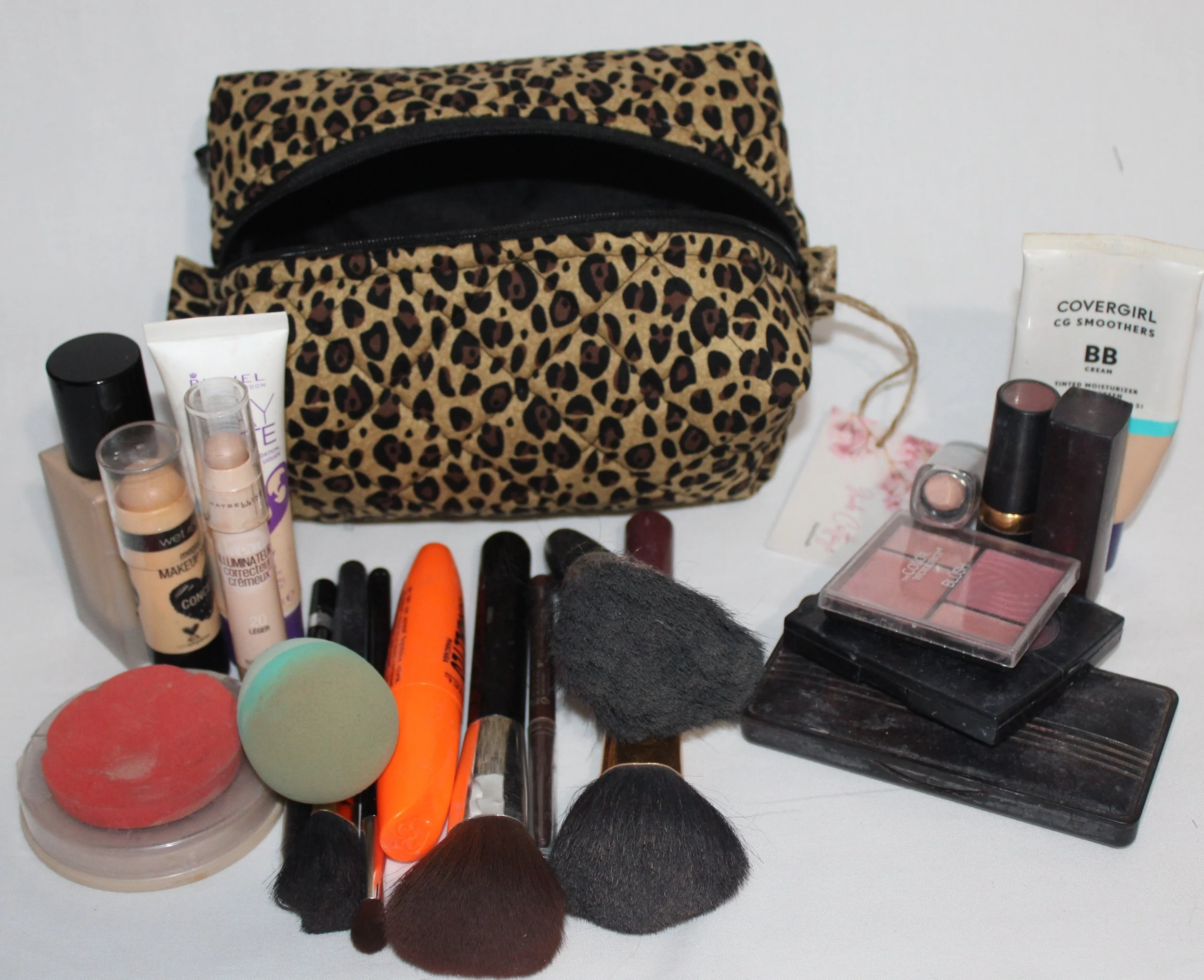 Sahara small, quilted travel pouch in cheetah print displayed with cosmetics and hygiene products arranged in front to show size.